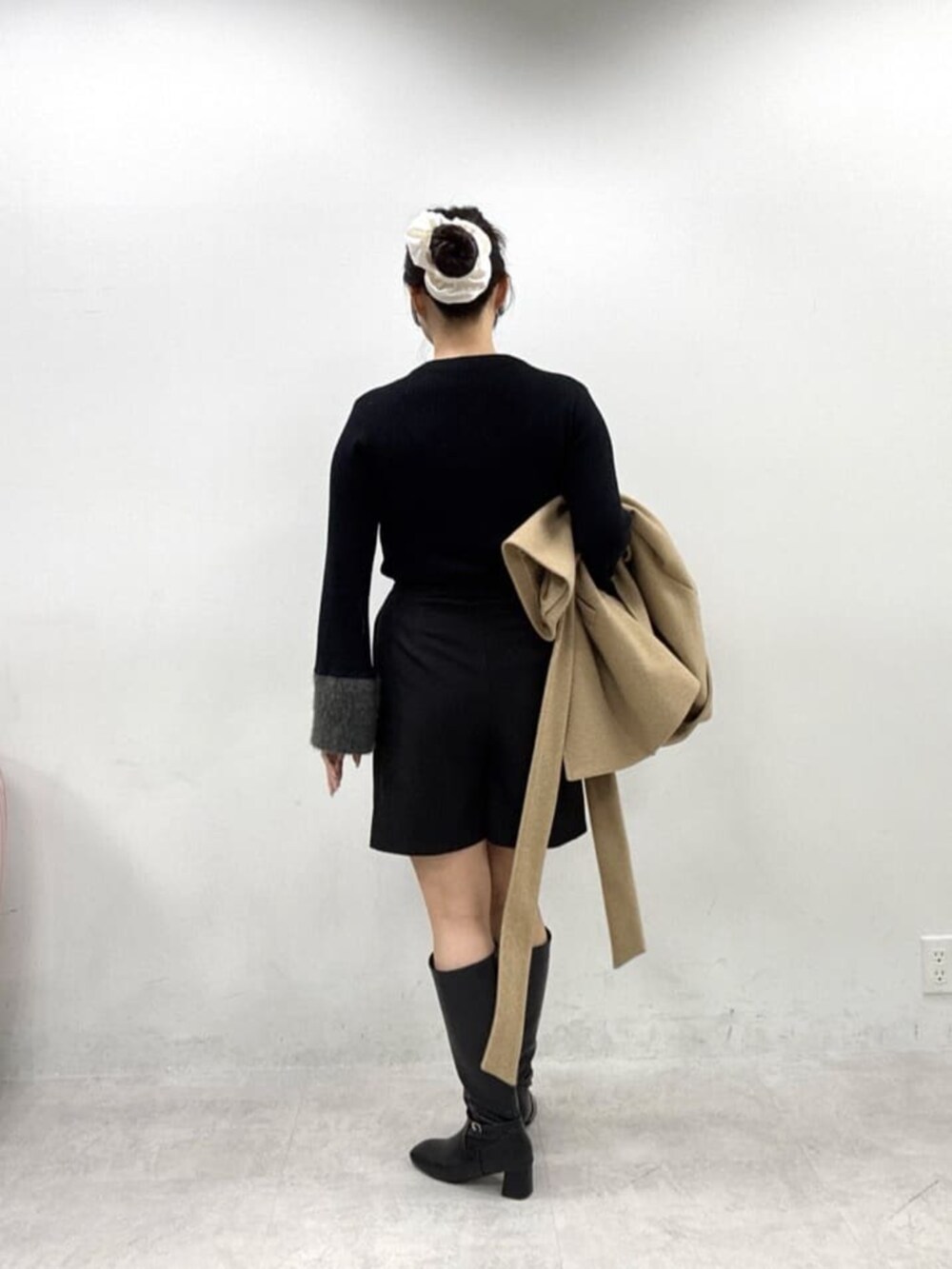 ブラック系のブーツ、ブラック系のスカート、ブラック系のニット/セーターを着用したレディースの秋コーディネートの3枚目の写真