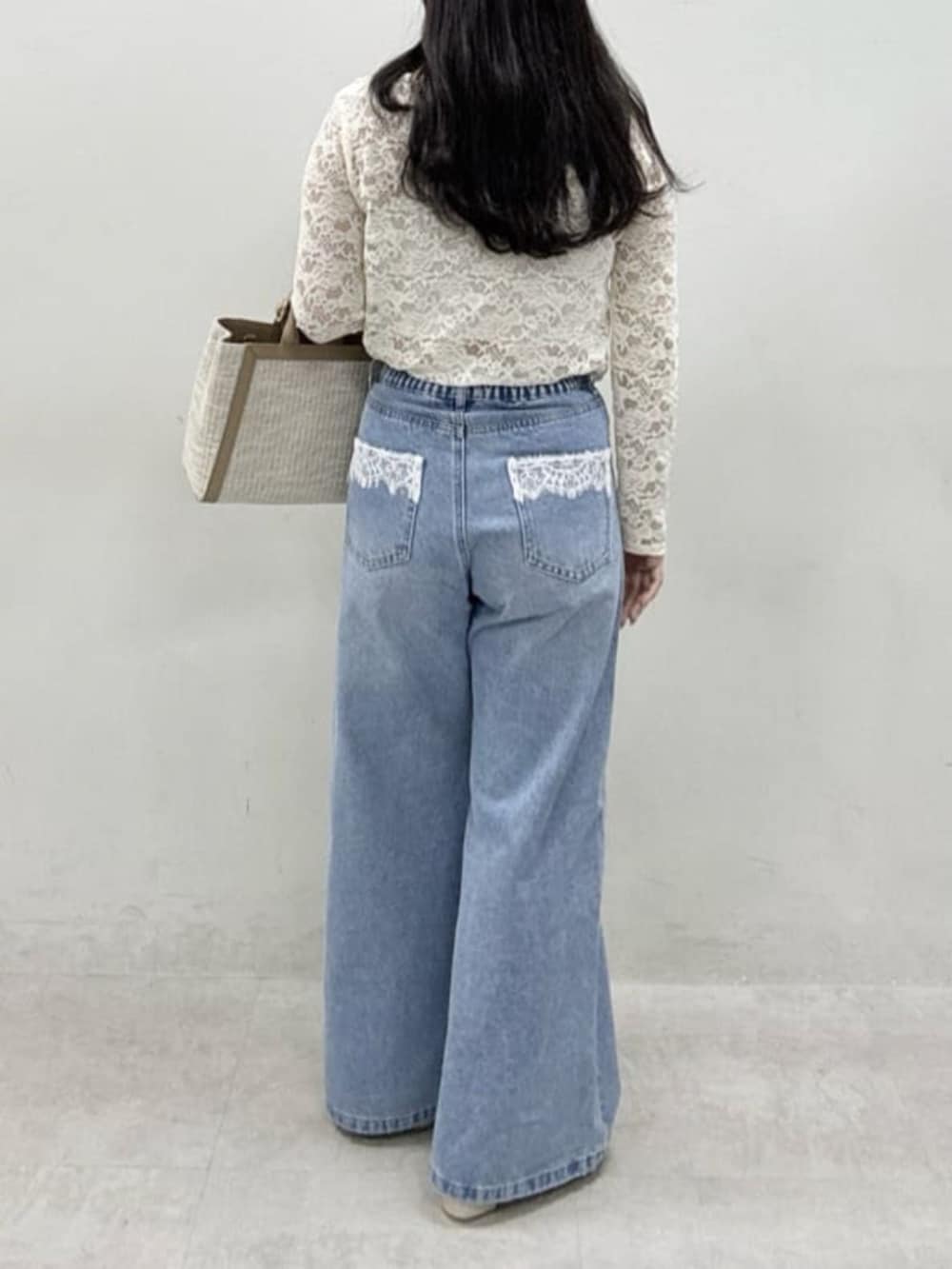 ホワイト系のTシャツ/カットソー、ブルー系のデニムパンツ、ベージュ系のハンドバッグを着用したレディースの冬コーディネートの3枚目の写真