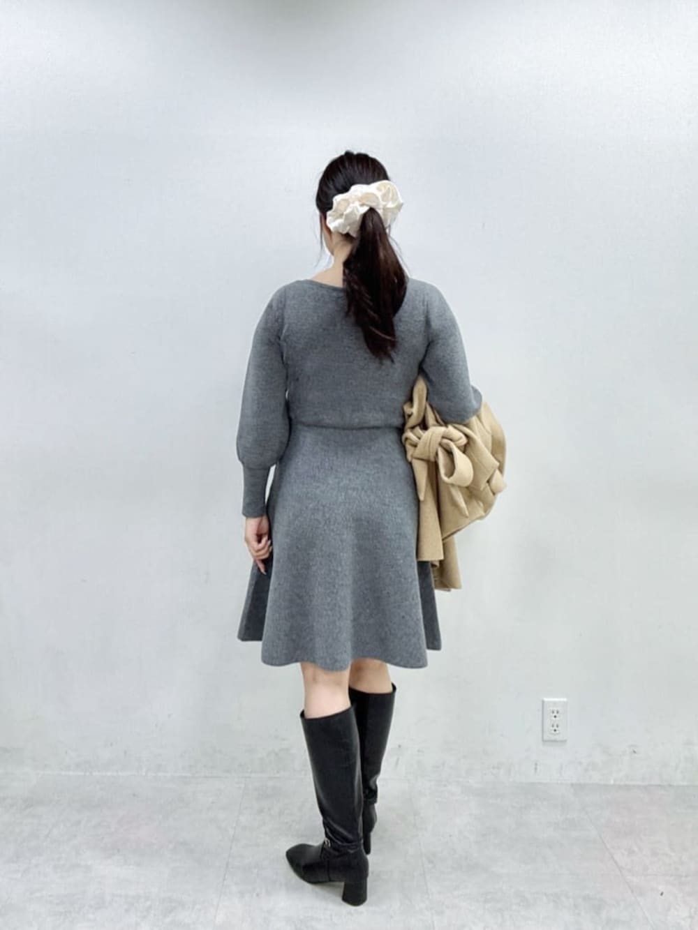 ブラック系のブーツ、ベージュ系のその他アウター、グレー系のワンピースを着用したレディースの秋コーディネートの3枚目の写真