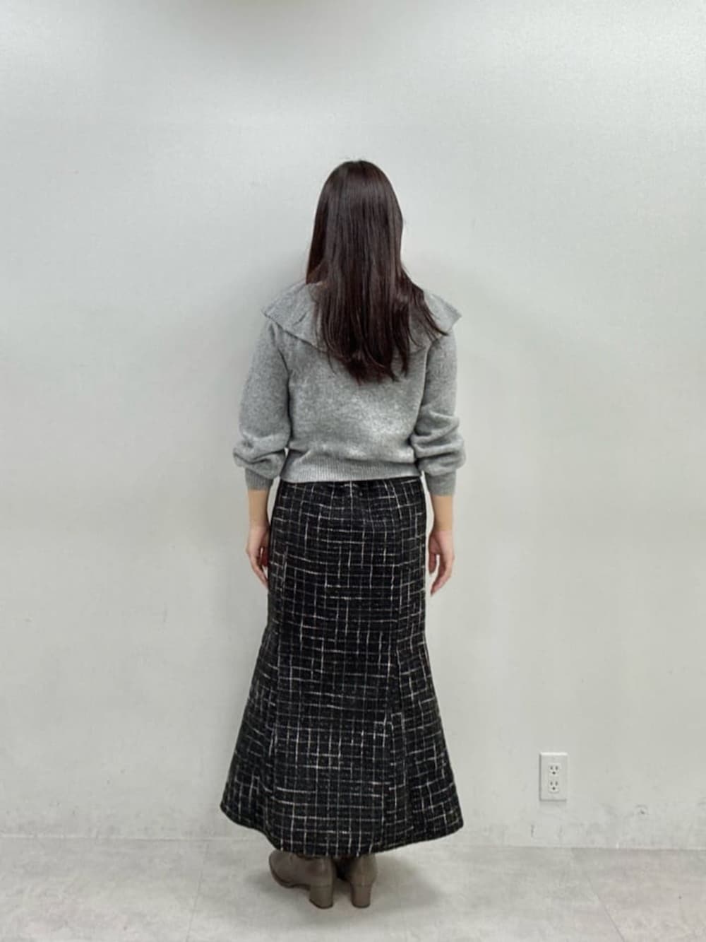 ブラック系のスカート、グレー系のニット/セーターを着用したレディースの秋コーディネートの3枚目の写真