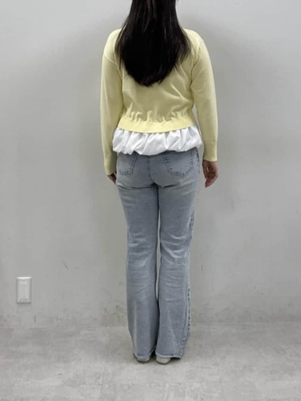 ブルー系のデニムパンツ、ホワイト系のサンダル、イエロー系のニット/セーターを着用したレディースの冬コーディネートの3枚目の写真