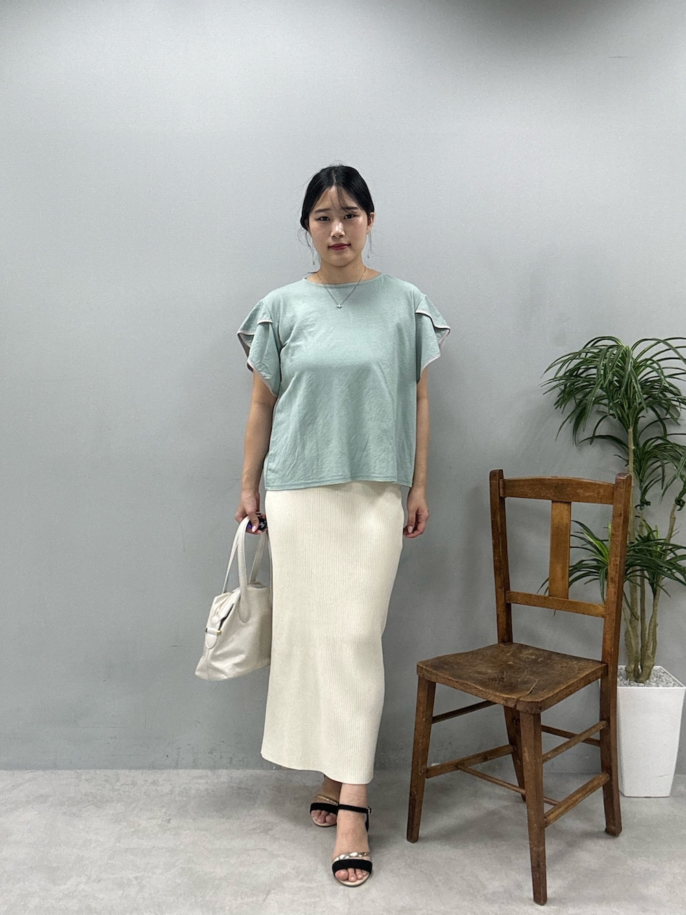 ホワイト系のショルダーバッグ、グリーン系のTシャツ/カットソー、ホワイト系のスカートを着用したレディースの春コーディネートの2枚目の写真