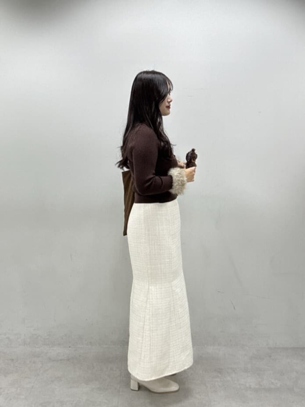 ホワイト系のスカート、ブラウン系のカーディガン/ボレロ、ブラウン系のトートバッグを着用したレディースの冬コーディネートの2枚目の写真