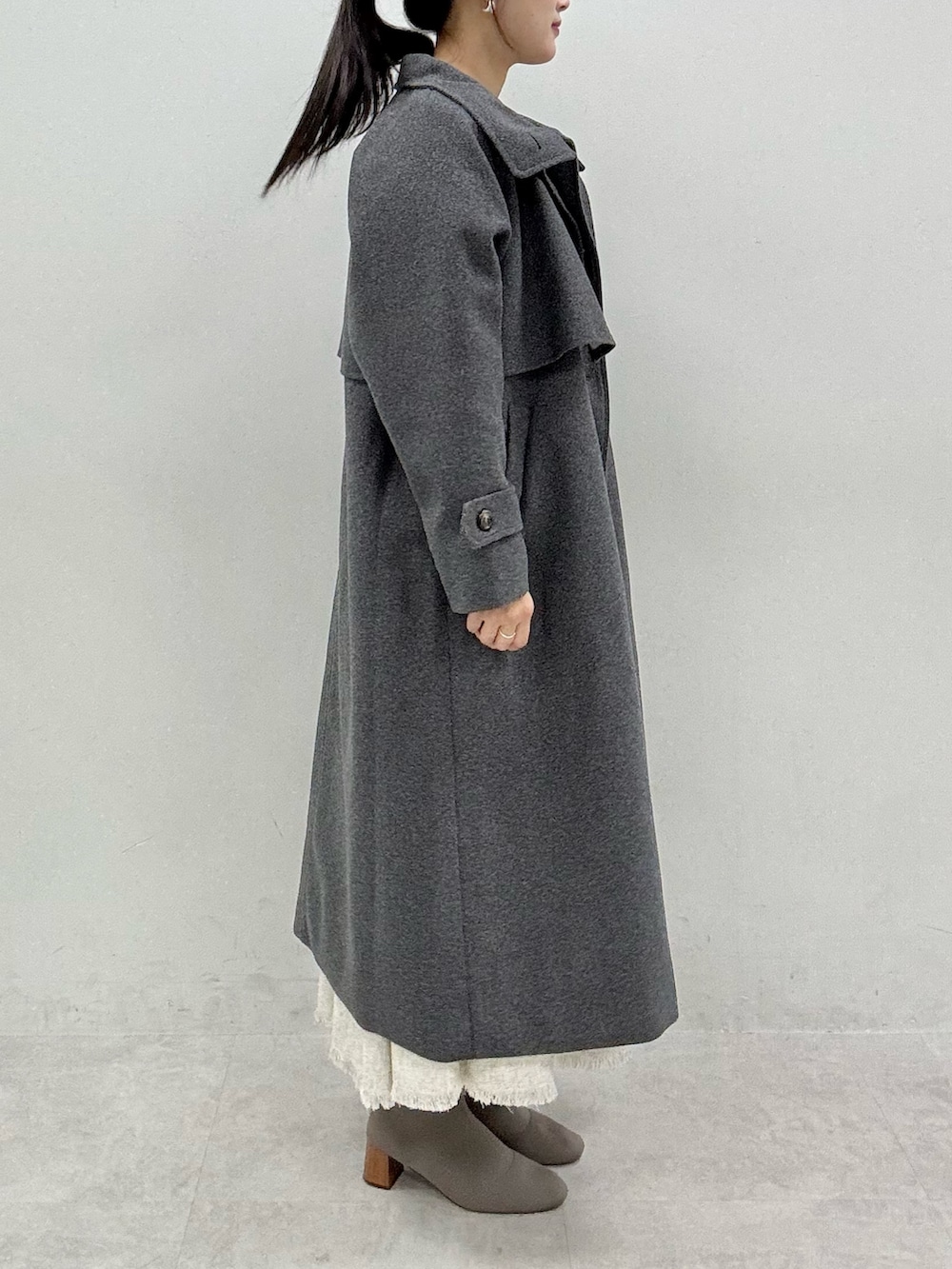 ブラック系のニット/セーター、グレー系のステンカラーコート、ホワイト系のワンピースを着用したレディースの秋コーディネートの3枚目の写真