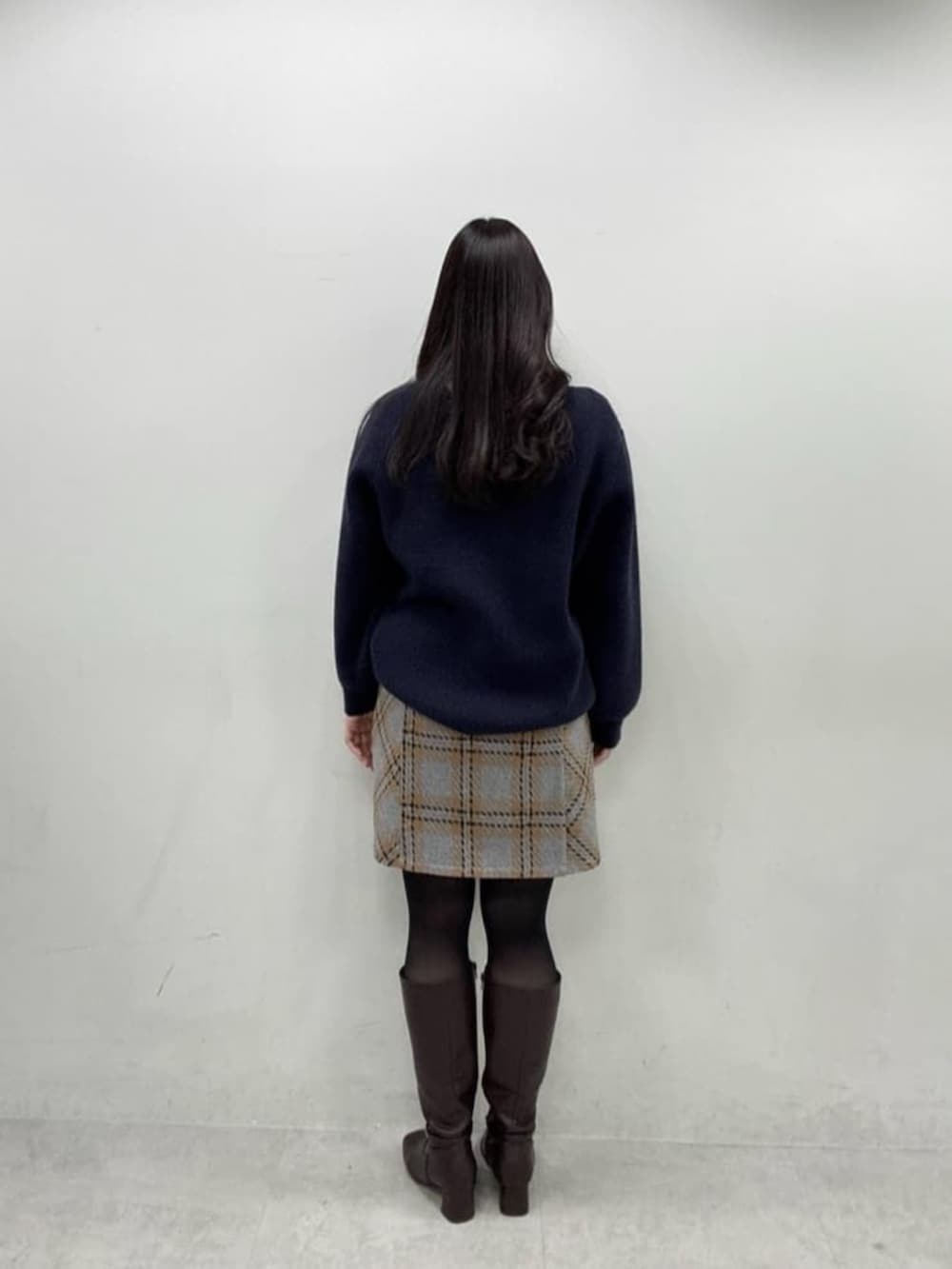 ブルー系のニット/セーター、グレー系のスカート、ブラウン系のブーツを着用したレディースの秋コーディネートの3枚目の写真