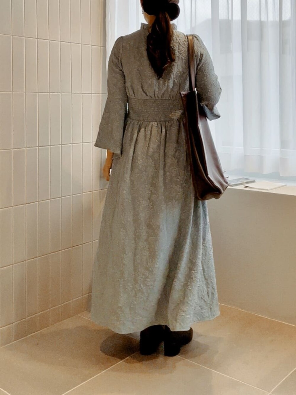 ブラウン系のトートバッグ、ブルー系のワンピースを着用したレディースの冬コーディネートの3枚目の写真