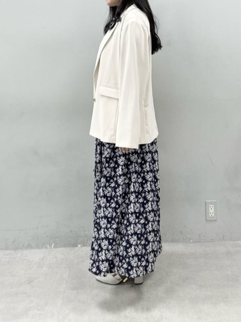 ホワイト系のテーラードジャケット、ホワイト系のハンドバッグ、グレー系のサンダルを着用したレディースの冬コーディネートの2枚目の写真