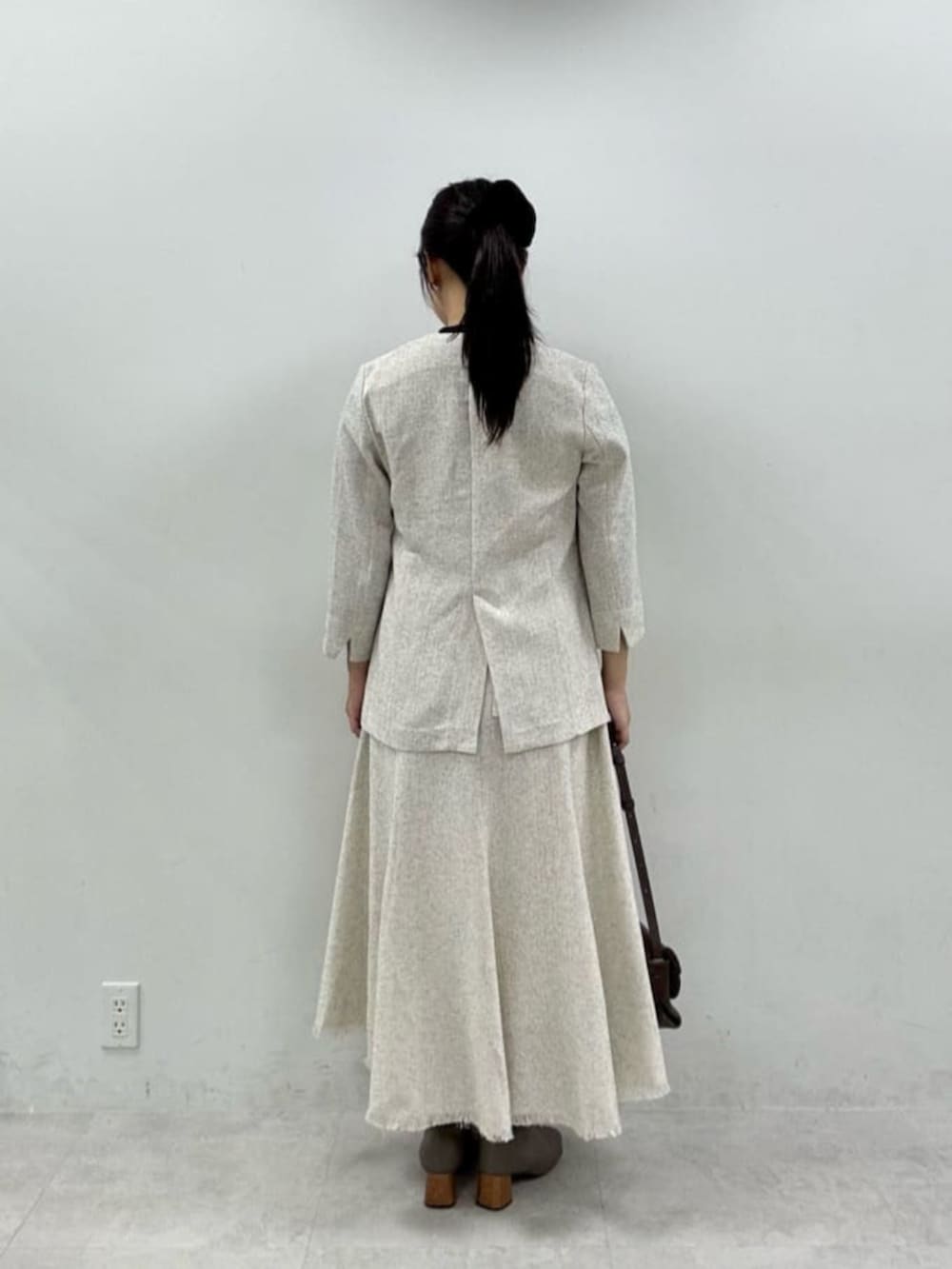 ブラック系のニット/セーター、ホワイト系のワンピース、ホワイト系のノーカラージャケットを着用したレディースの秋コーディネートの3枚目の写真