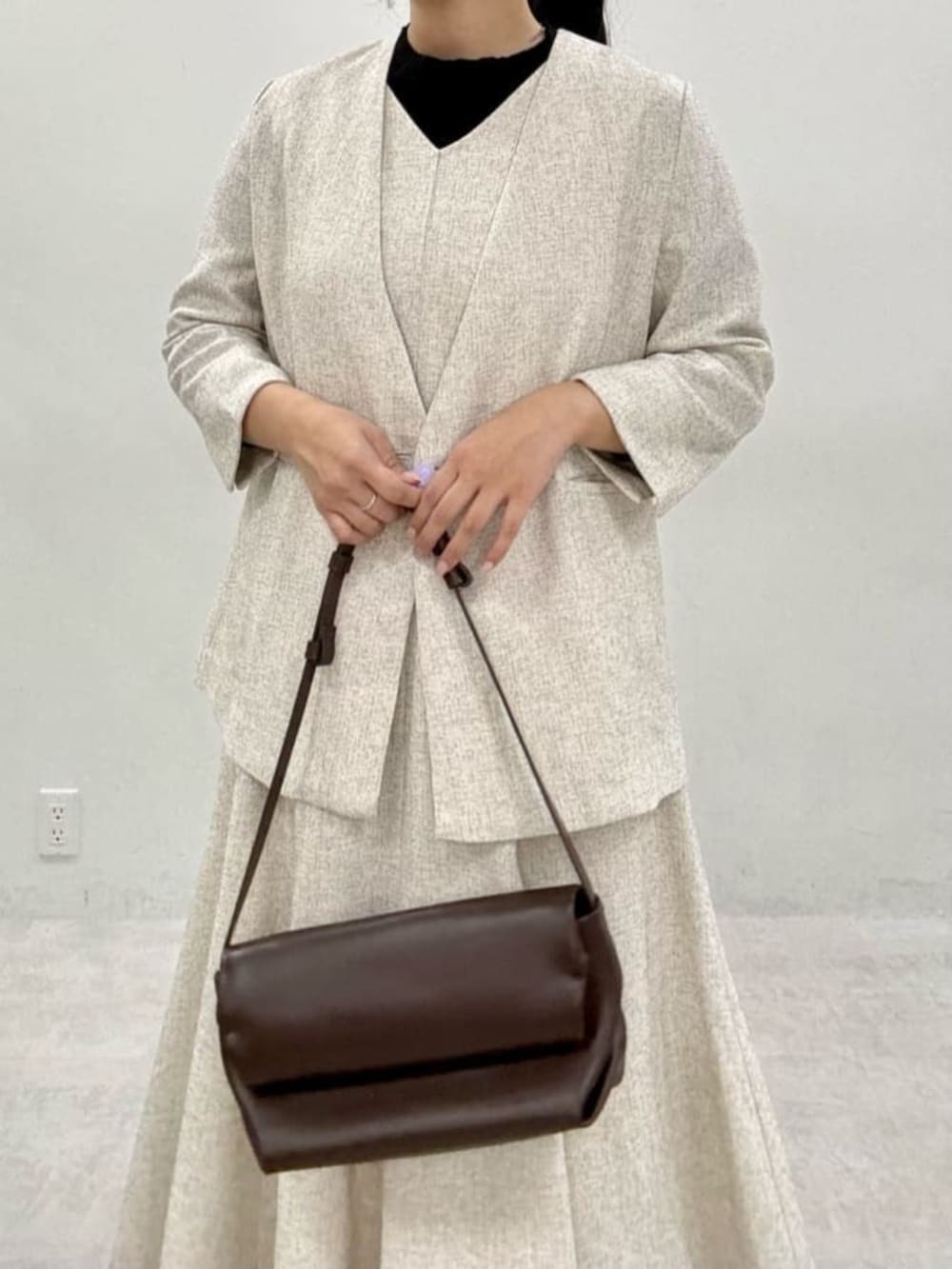 ブラック系のニット/セーター、ホワイト系のワンピース、ホワイト系のノーカラージャケットを着用したレディースの秋コーディネートの4枚目の写真