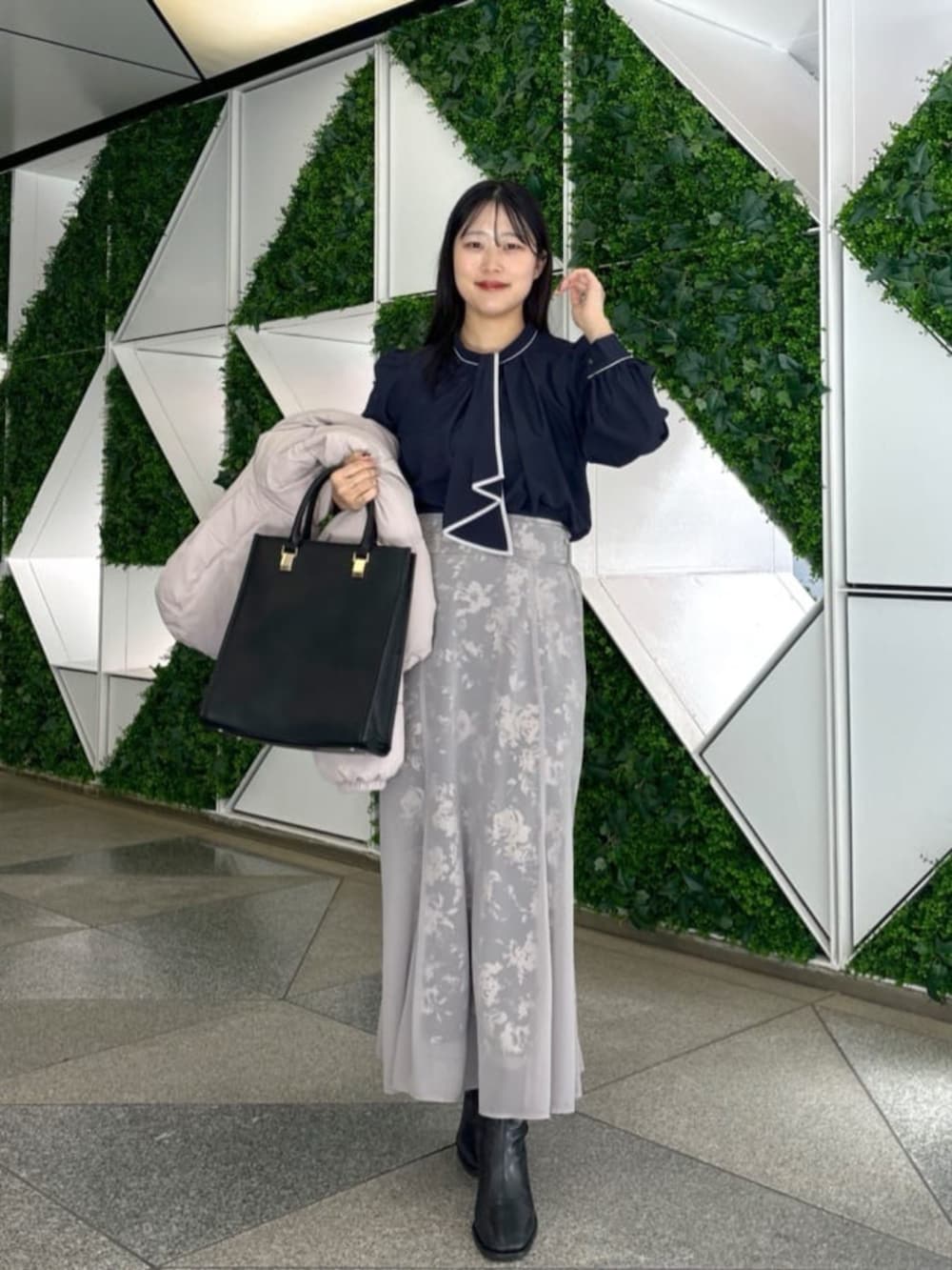 ブラック系のスカート、ベージュ系のダウンジャケット/コート、ブルー系のシャツ/ブラウスを着用したレディースの秋コーディネートの3枚目の写真