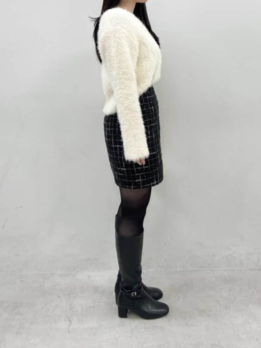 ブラック系のスカート、ホワイト系のニット/セーターを着用したレディースの冬コーディネートの2枚目の写真