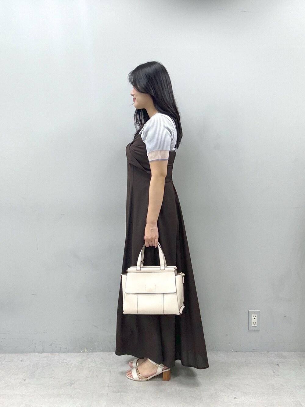 ブラウン系のワンピース、ホワイト系のショルダーバッグ、グレー系のニット/セーターを着用したレディースの春コーディネートの2枚目の写真
