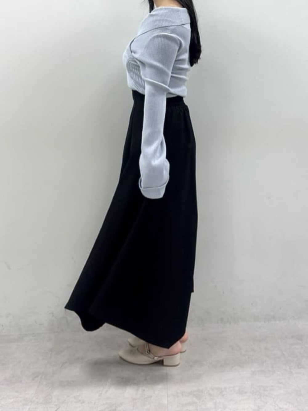 ブラック系のスカート、ブルー系のニット/セーターを着用したレディースの春コーディネートの2枚目の写真