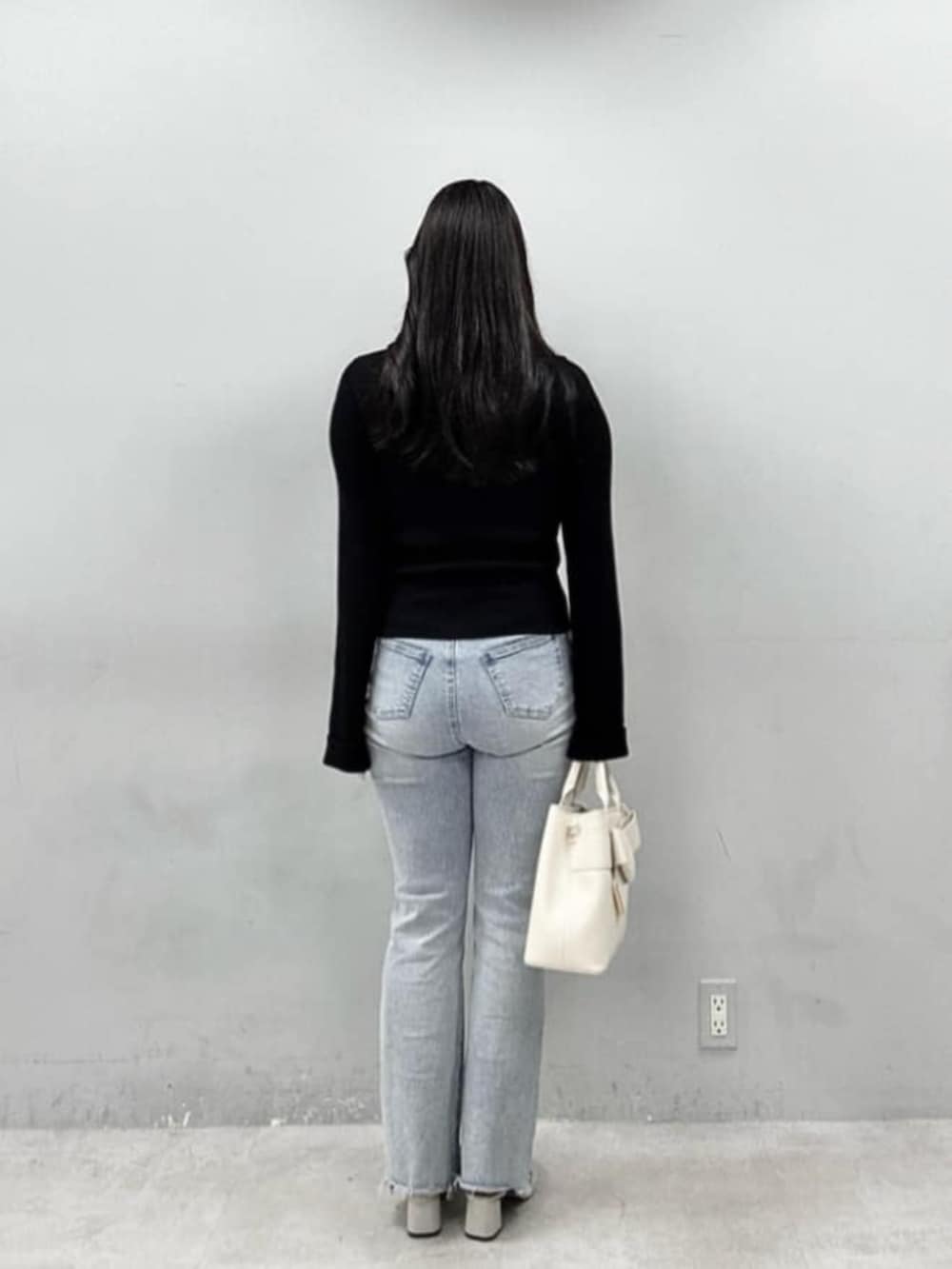 ブルー系のデニムパンツ、ブラック系のニット/セーターを着用したレディースの春コーディネートの2枚目の写真