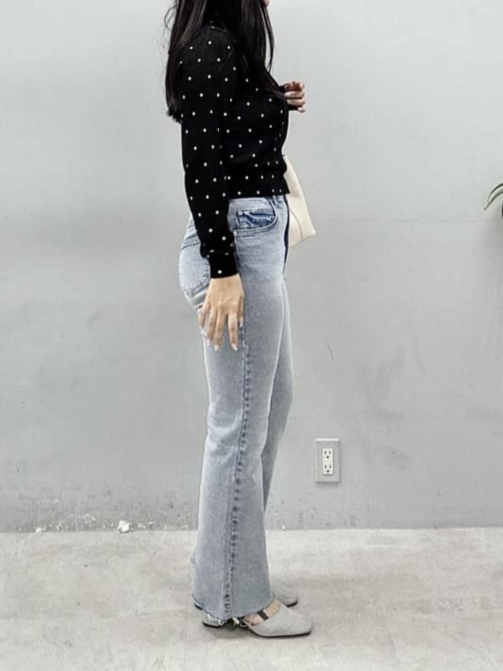 ブルー系のデニムパンツ、ホワイト系のショルダーバッグ、ブラック系のカーディガン/ボレロを着用したレディースの春コーディネートの2枚目の写真