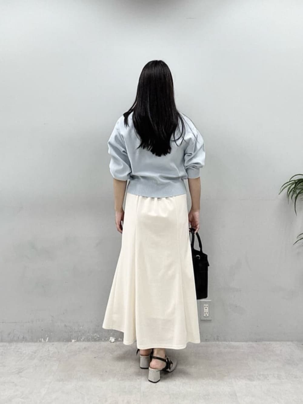 ブラック系のショルダーバッグ、ホワイト系のスカート、ブルー系のカーディガン/ボレロを着用したレディースの春コーディネートの3枚目の写真