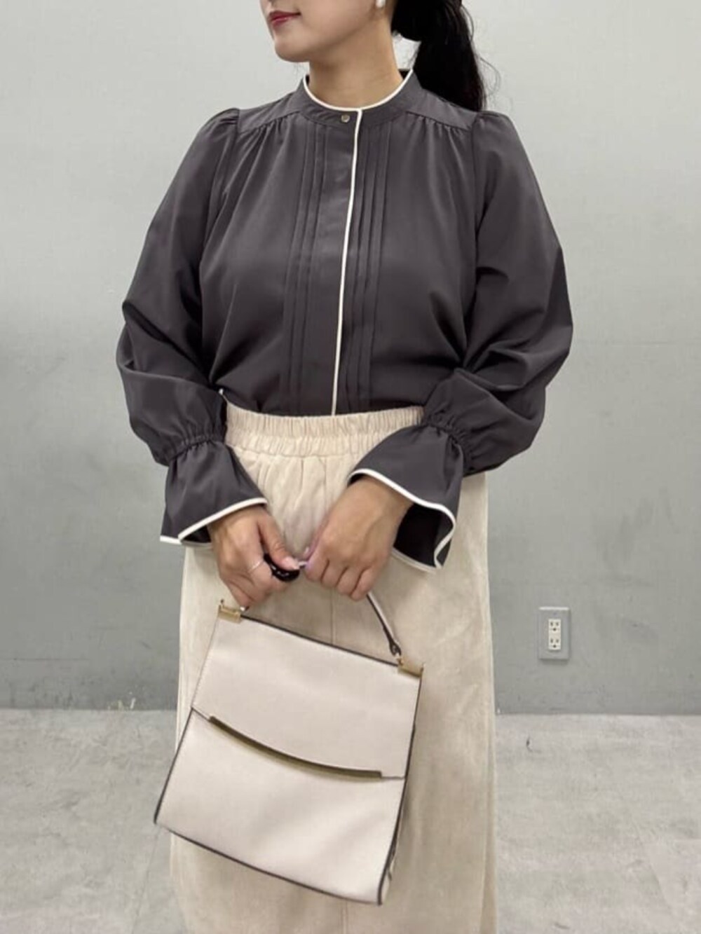 グレー系のシャツ/ブラウス、ベージュ系のスカート、ホワイト系のショルダーバッグを着用したレディースの秋コーディネートの3枚目の写真