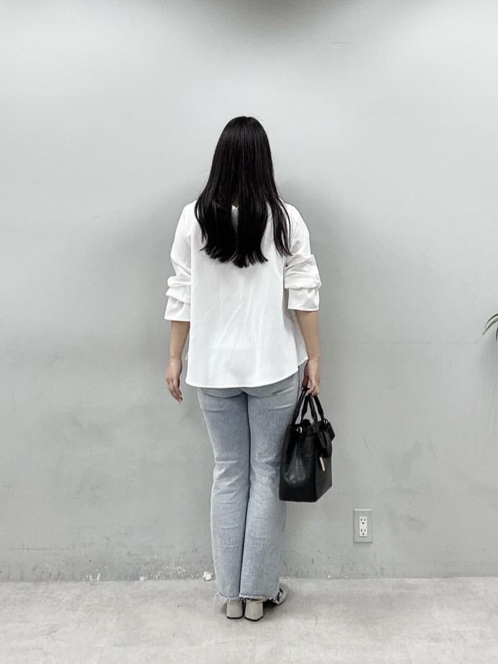 ブルー系のデニムパンツ、ブラック系のショルダーバッグ、ホワイト系のシャツ/ブラウスを着用したレディースの春コーディネートの3枚目の写真
