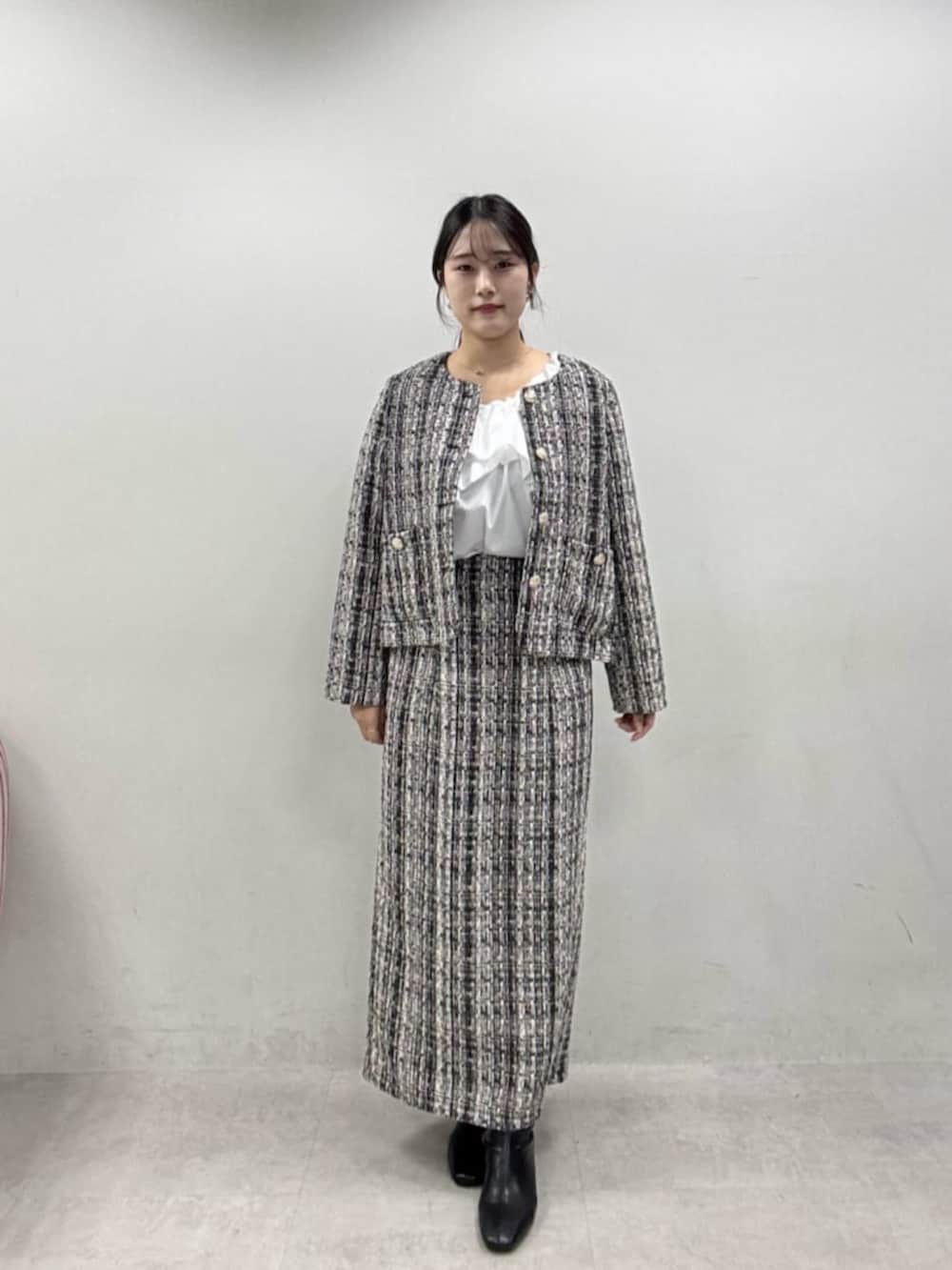 グレー系のスカート、グレー系のノーカラージャケット、ブラック系のブーツを着用したレディースの秋コーディネートの5枚目の写真