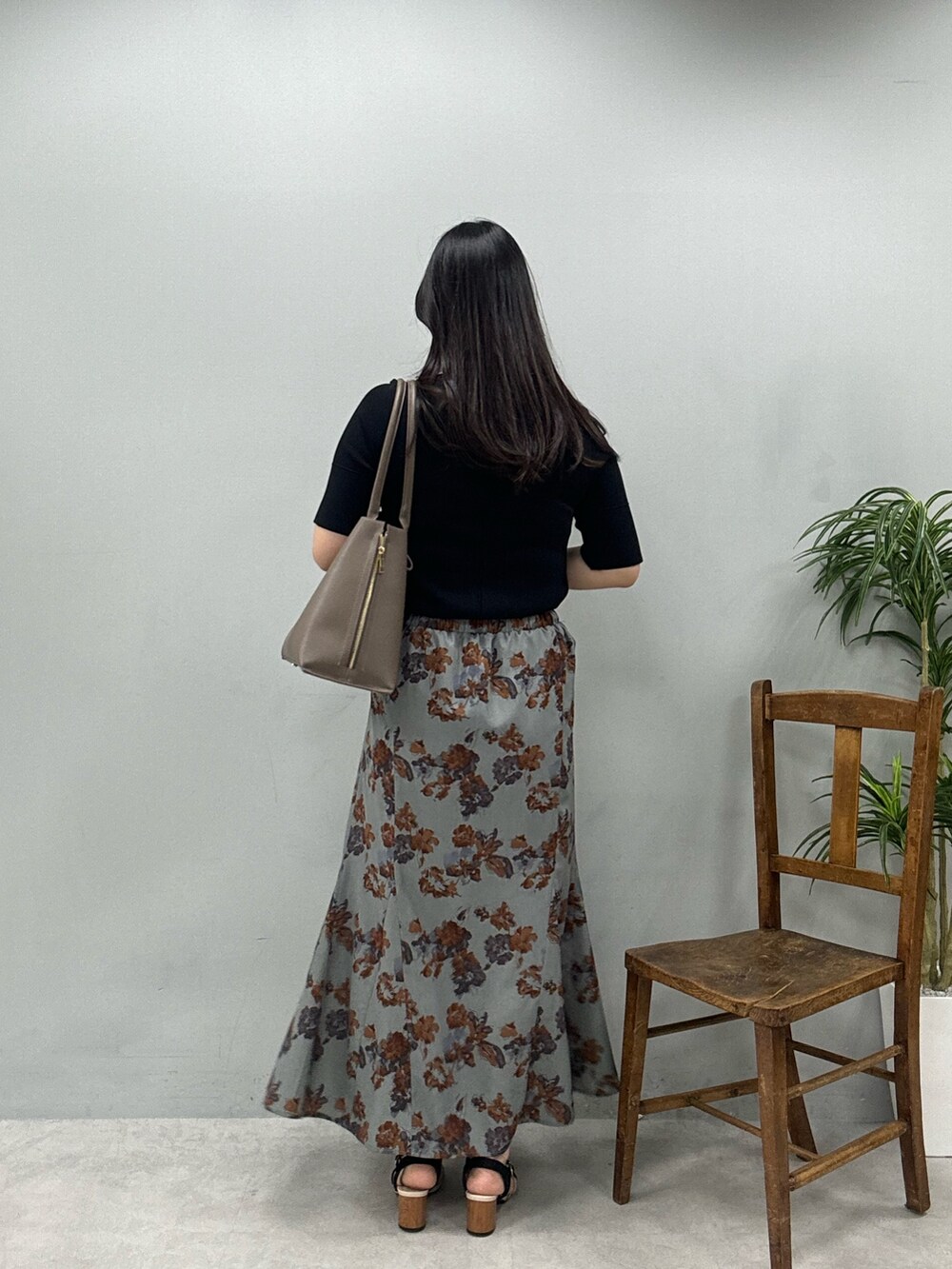 ブラウン系のショルダーバッグ、グレー系のスカート、ブラック系のニット/セーターを着用したレディースの春コーディネートの3枚目の写真