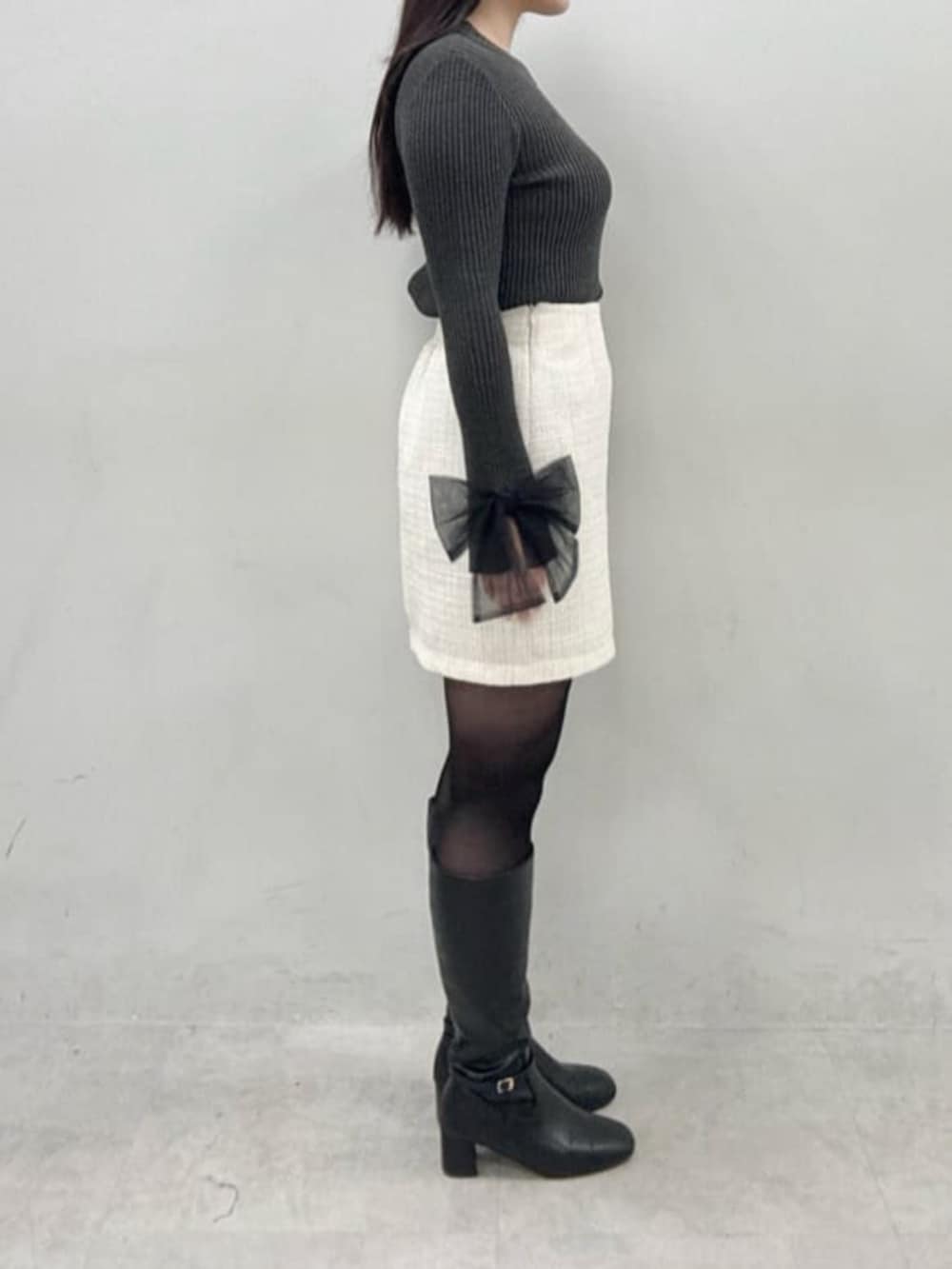 ホワイト系のスカート、グレー系のニット/セーターを着用したレディースの冬コーディネートの2枚目の写真