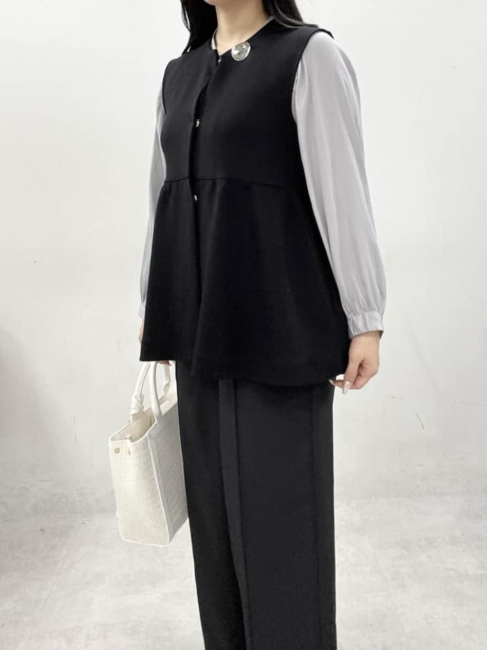 ホワイト系のハンドバッグ、グレー系のサンダル、ブラック系のスラックスを着用したレディースの冬コーディネートの5枚目の写真