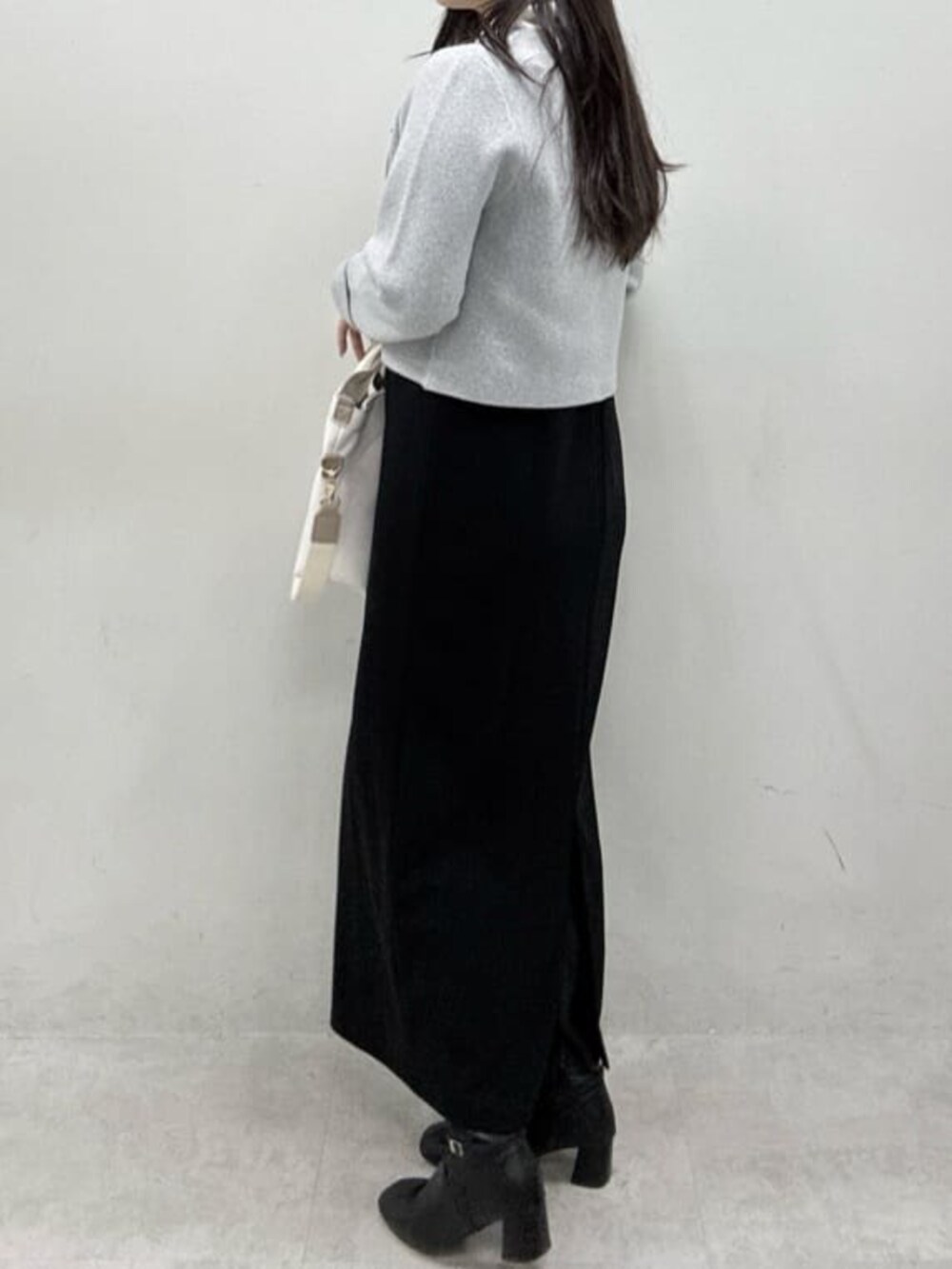 グレー系のカーディガン/ボレロ、ブラック系のワンピース、ホワイト系のトートバッグを着用したレディースの冬コーディネートの6枚目の写真