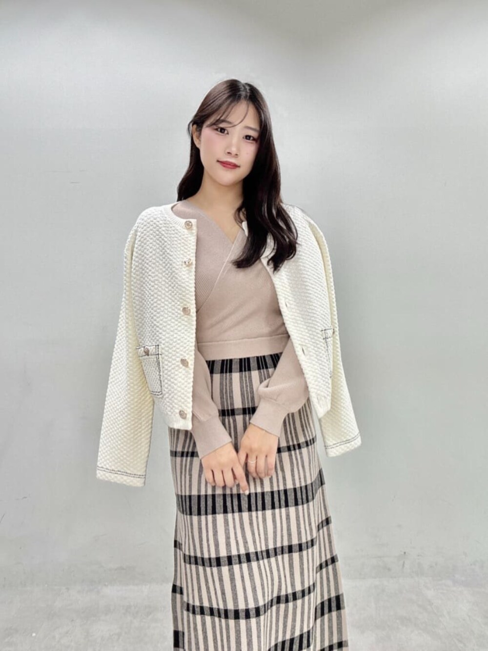 ベージュ系のワンピース、ホワイト系のニット/セーターを着用したレディースの秋コーディネートの2枚目の写真