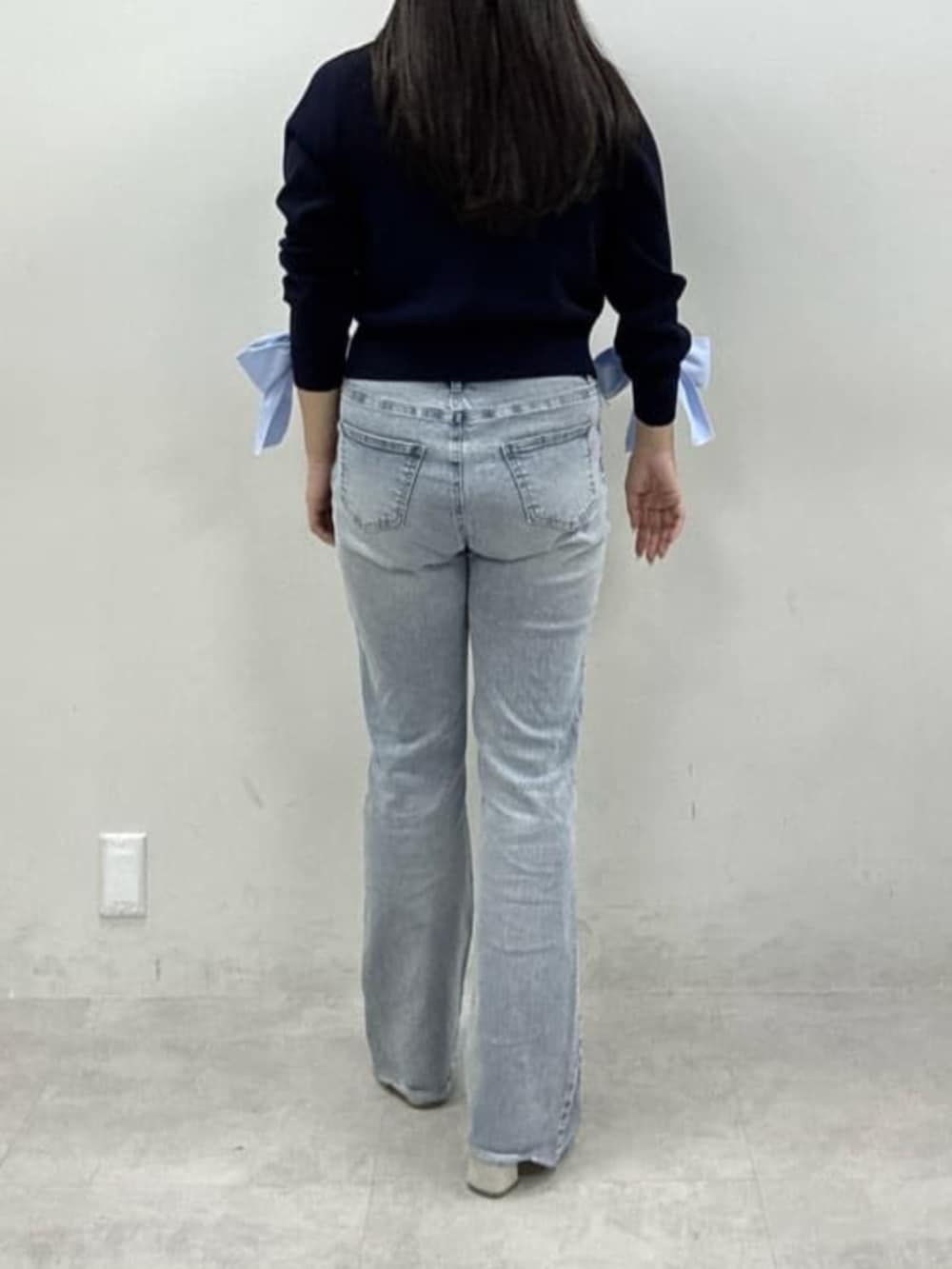 ブルー系のデニムパンツ、ホワイト系のサンダル、ブルー系のカーディガン/ボレロを着用したレディースの冬コーディネートの3枚目の写真