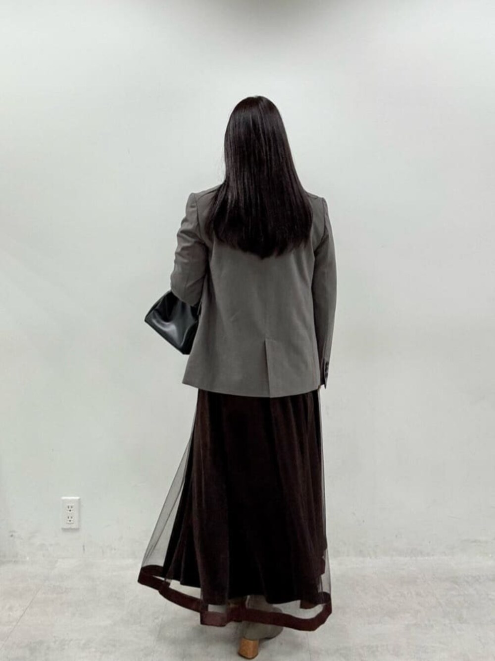 ブラウン系のスカート、グレー系のテーラードジャケットを着用したレディースの秋コーディネートの3枚目の写真