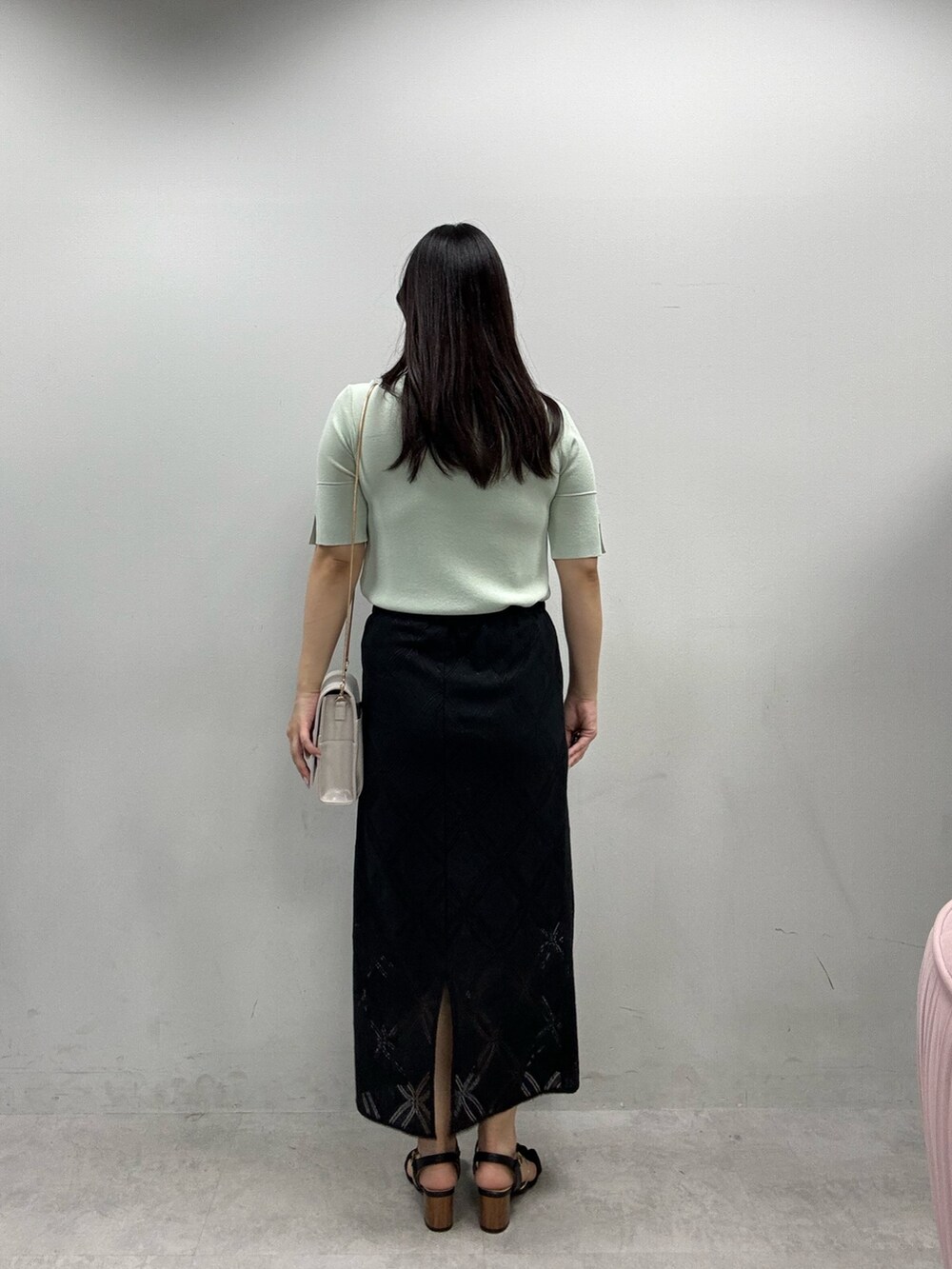 ホワイト系のショルダーバッグ、ブラック系のスカート、グリーン系のニット/セーターを着用したレディースの春コーディネートの3枚目の写真