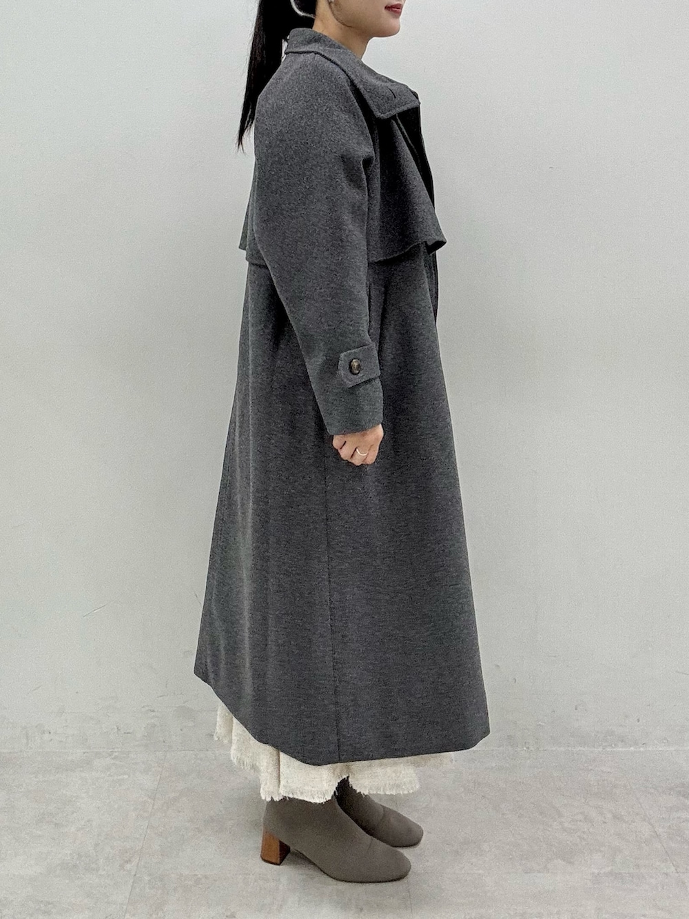 ブラック系のニット/セーター、グレー系のステンカラーコート、ホワイト系のワンピースを着用したレディースの秋コーディネートの2枚目の写真