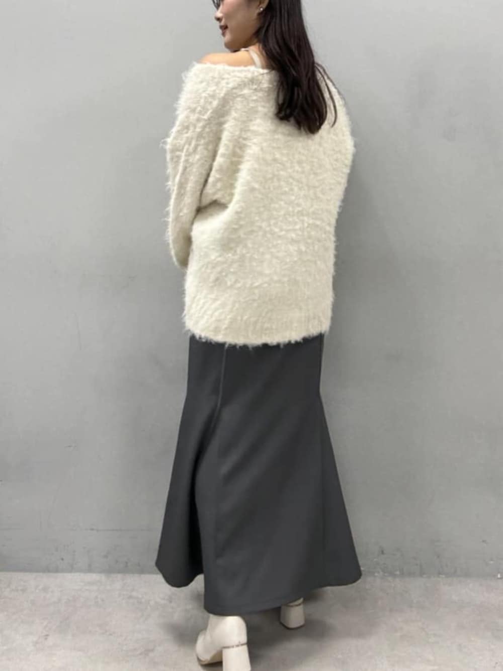 グレー系のスカート、ホワイト系のカーディガン/ボレロを着用したレディースの秋コーディネートの2枚目の写真