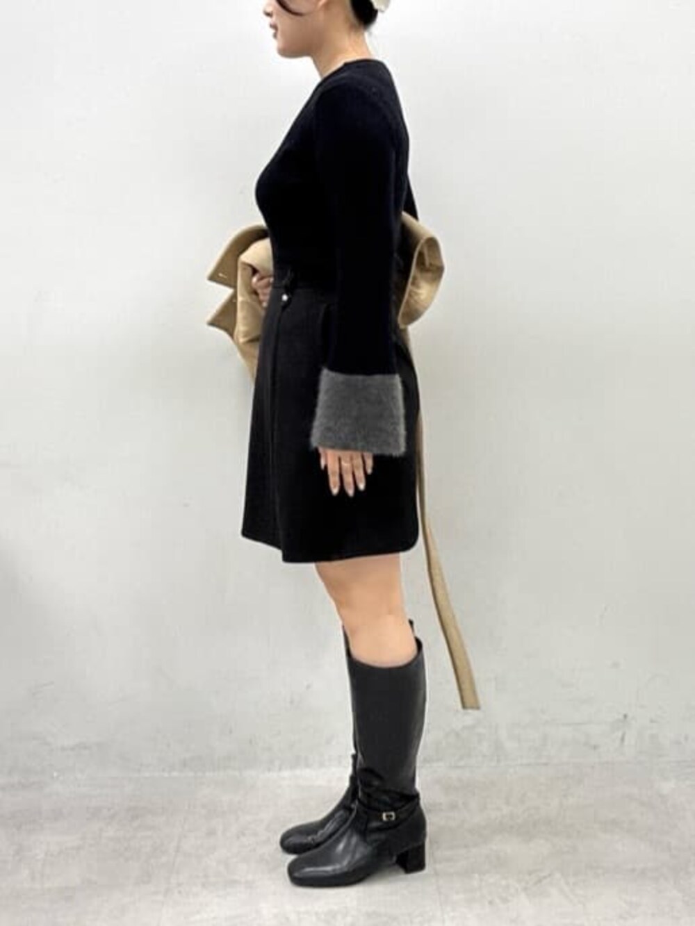 ブラック系のブーツ、ブラック系のスカート、ブラック系のニット/セーターを着用したレディースの秋コーディネートの2枚目の写真