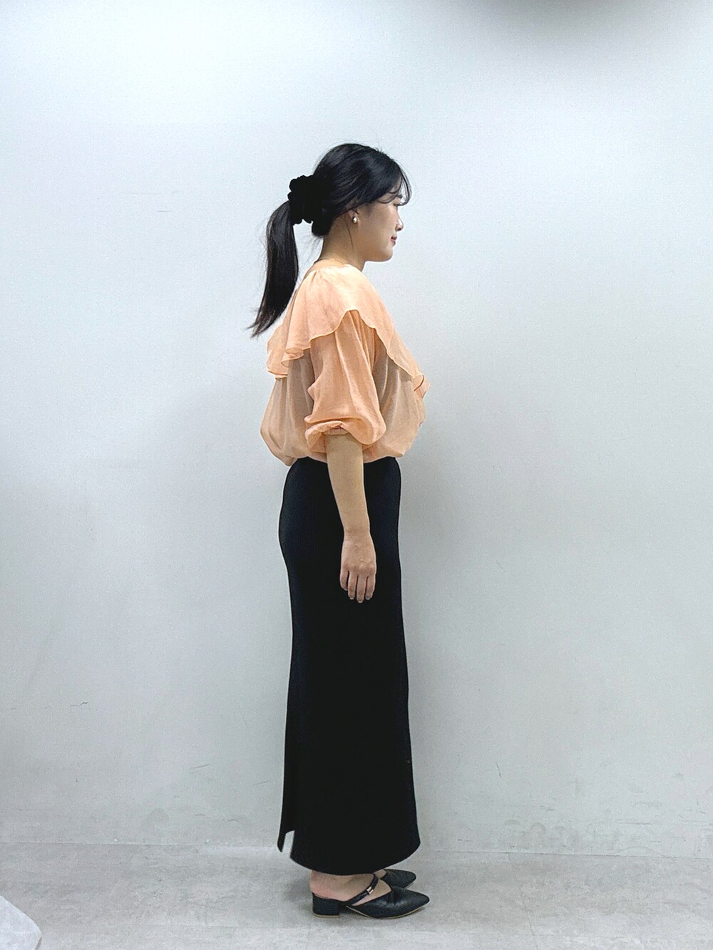 オレンジ系のシャツ/ブラウス、ブラック系のスカートを着用したレディースの春コーディネートの2枚目の写真