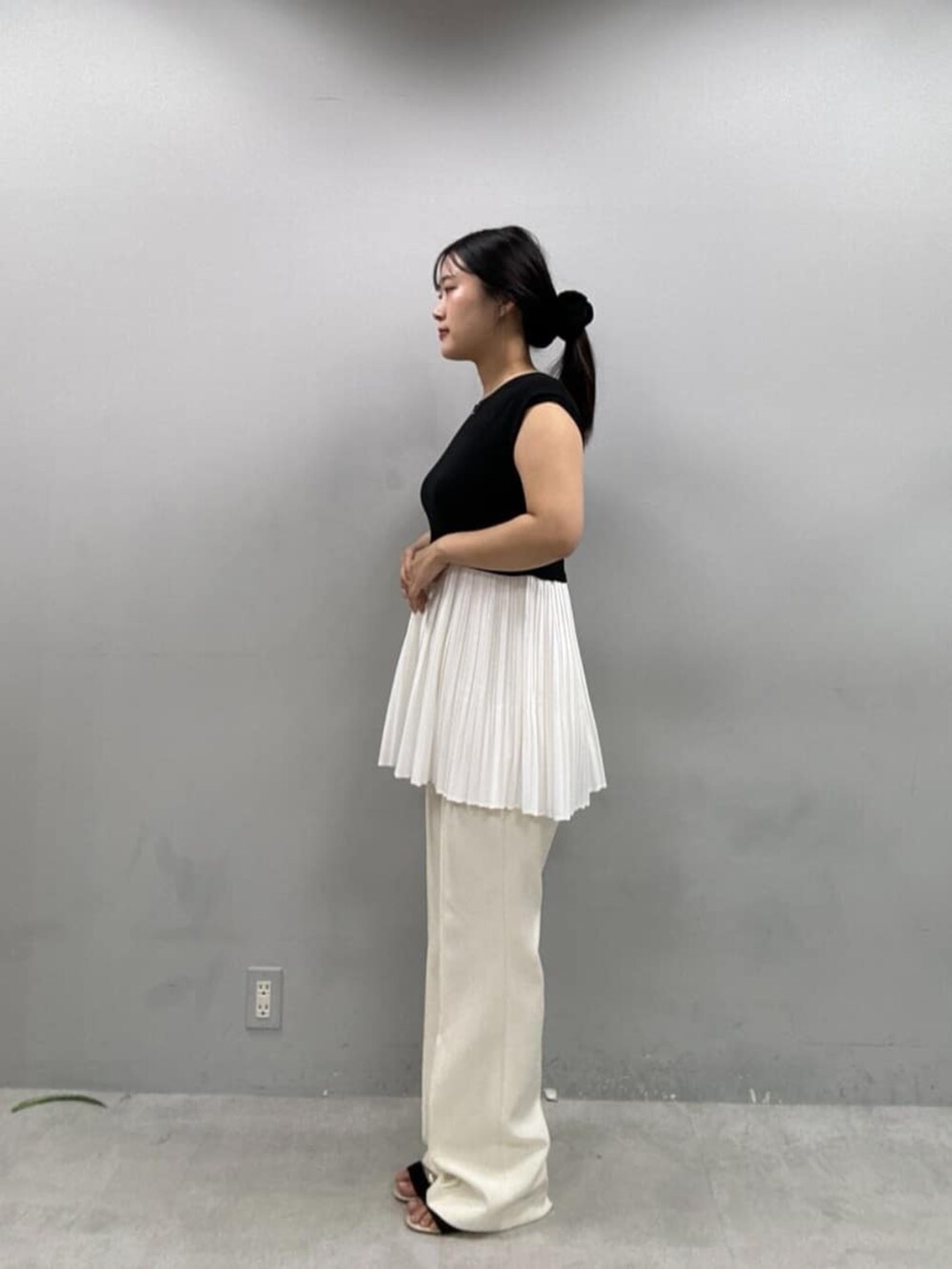 ベージュ系のショルダーバッグ、ホワイト系のその他パンツ、ブラック系のニット/セーターを着用したレディースの夏コーディネートの2枚目の写真