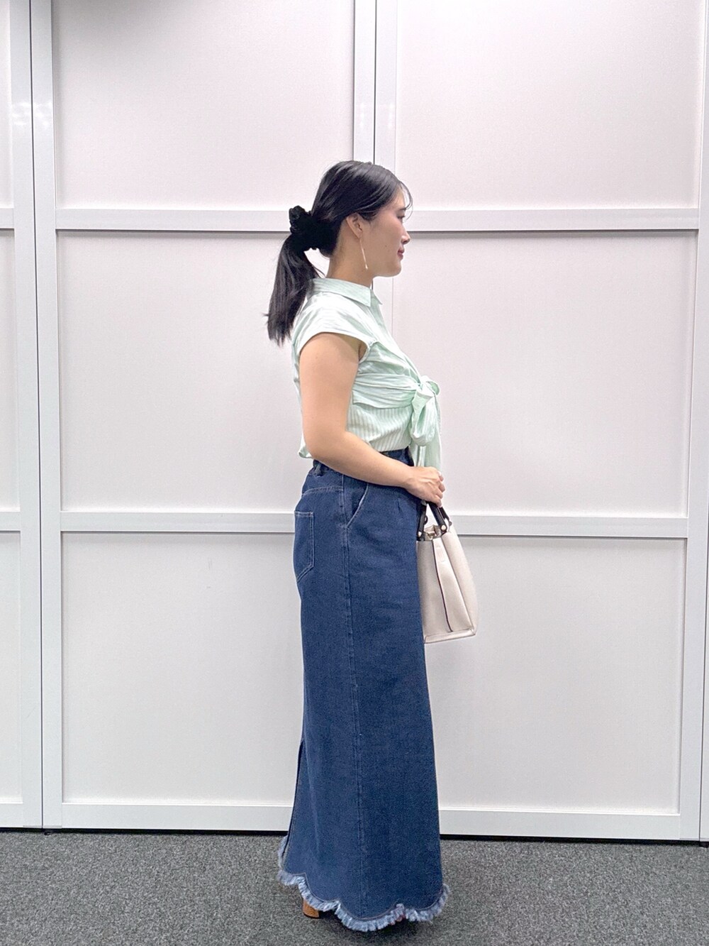 グレー系のショルダーバッグ、ブルー系のスカート、グリーン系のシャツ/ブラウスを着用したレディースの春コーディネートの2枚目の写真