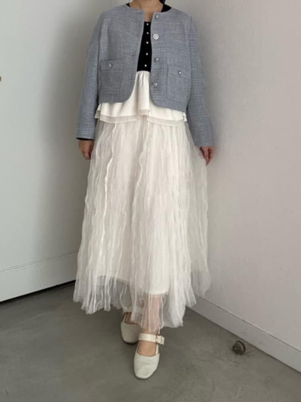 ブラック系のニット/セーター、ホワイト系のサンダル、ホワイト系のスカートを着用したレディースの冬コーディネートの4枚目の写真