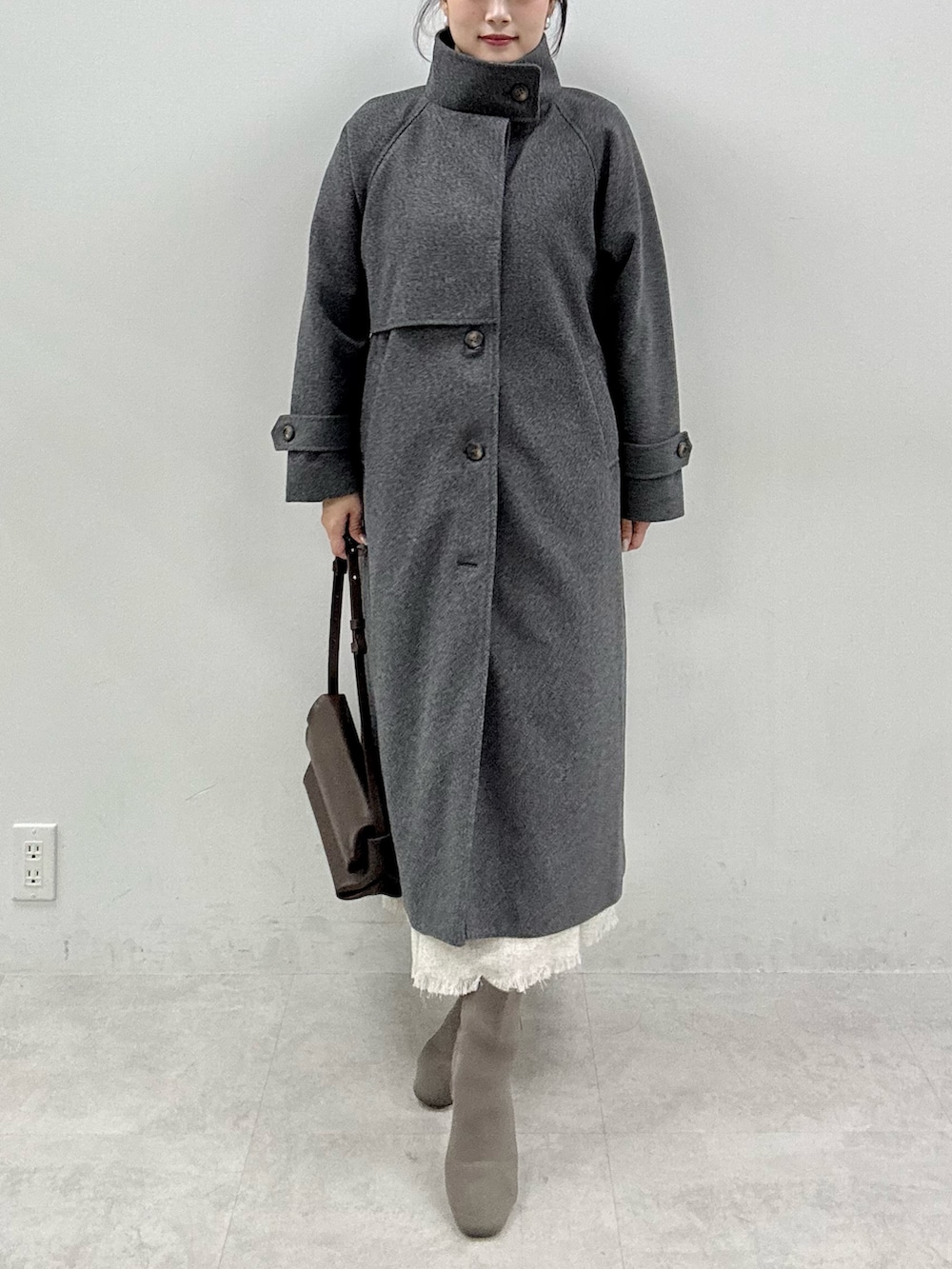 ブラック系のニット/セーター、グレー系のステンカラーコート、ホワイト系のワンピースを着用したレディースの秋コーディネートの6枚目の写真