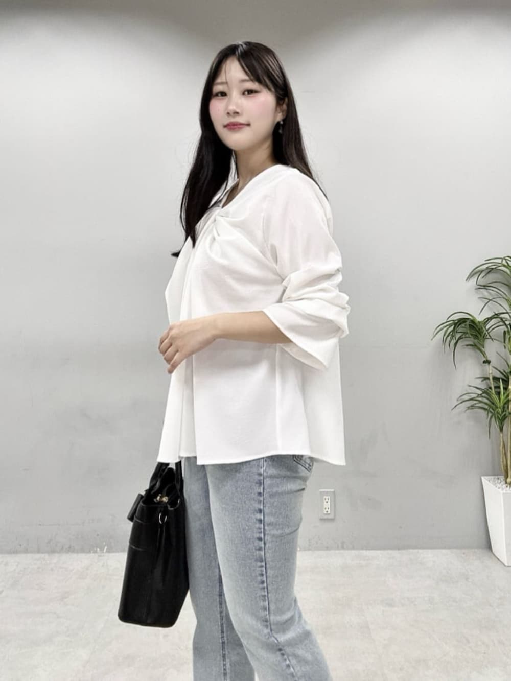 ブルー系のデニムパンツ、ブラック系のショルダーバッグ、ホワイト系のシャツ/ブラウスを着用したレディースの春コーディネートの6枚目の写真