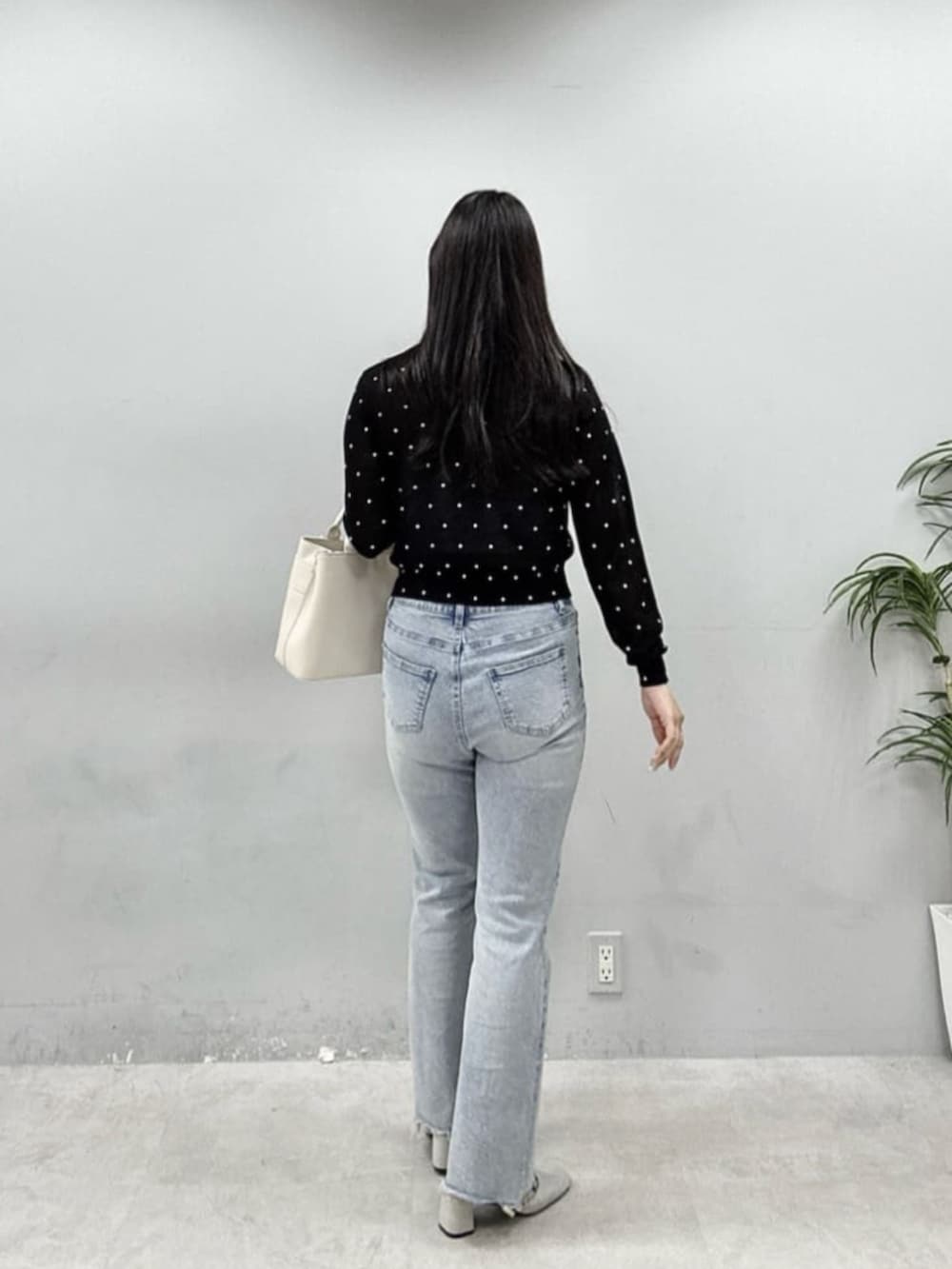 ブルー系のデニムパンツ、ホワイト系のショルダーバッグ、ブラック系のカーディガン/ボレロを着用したレディースの春コーディネートの3枚目の写真