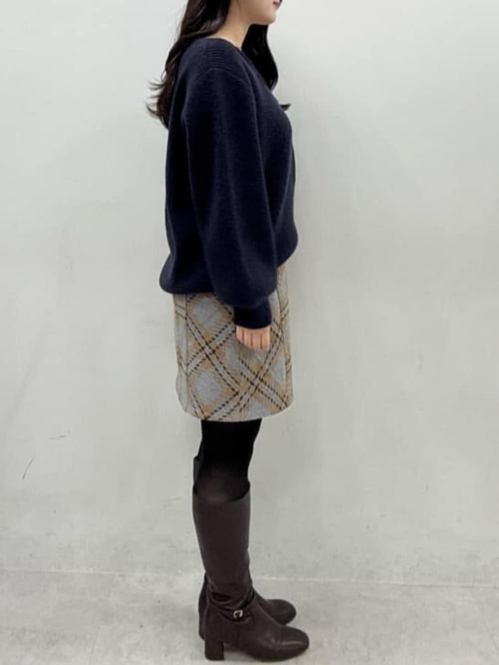 ブルー系のニット/セーター、グレー系のスカート、ブラウン系のブーツを着用したレディースの秋コーディネートの2枚目の写真