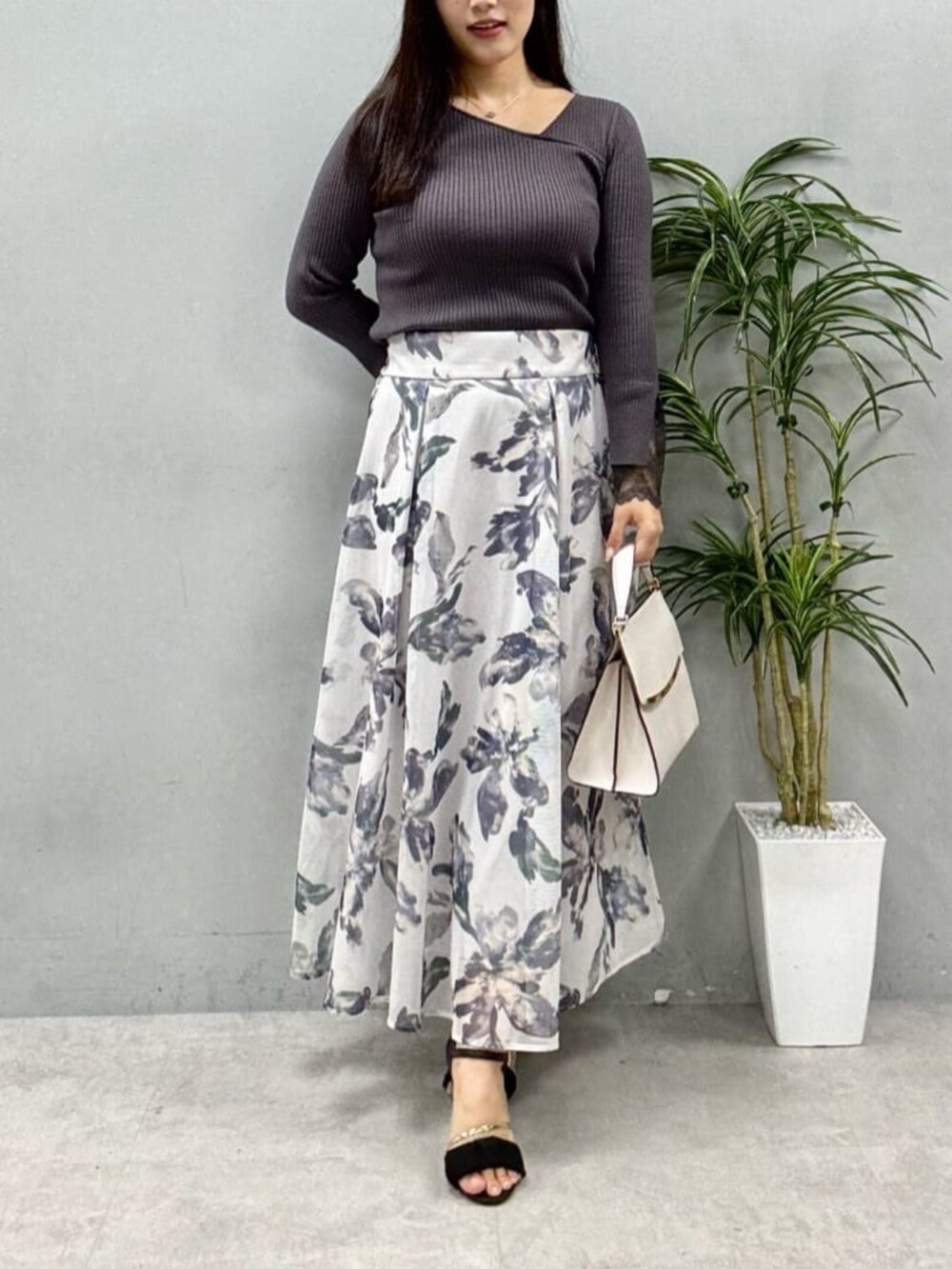グレー系のニット/セーター、ホワイト系のスカートを着用したレディースの夏コーディネートの4枚目の写真
