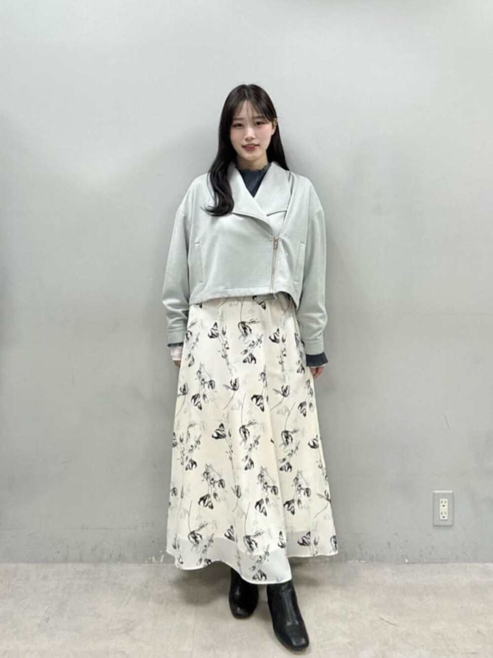 ホワイト系のスカート、グレー系のTシャツ/カットソー、グリーン系のライダースジャケットを着用したレディースの冬コーディネートの2枚目の写真