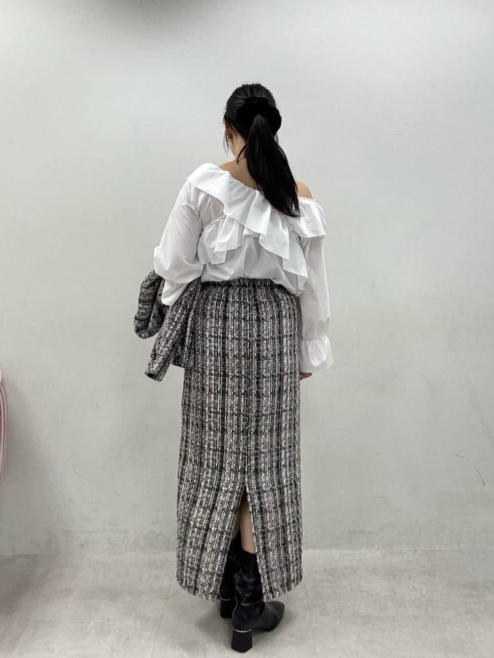 グレー系のスカート、グレー系のノーカラージャケット、ブラック系のブーツを着用したレディースの秋コーディネートの3枚目の写真