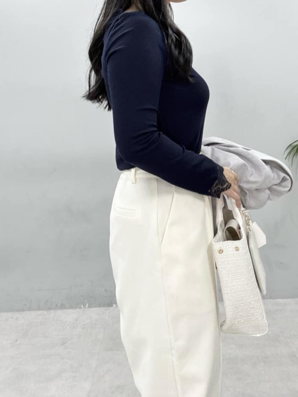 グレー系のテーラードジャケット、ホワイト系のハンドバッグ、ホワイト系のスラックスを着用したレディースの春コーディネートの6枚目の写真