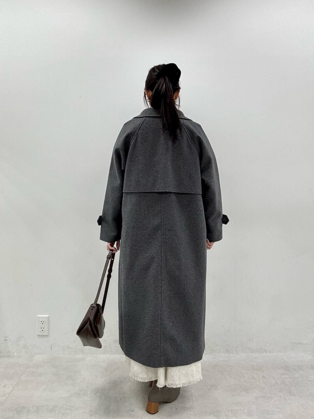 ブラック系のニット/セーター、グレー系のステンカラーコート、ホワイト系のワンピースを着用したレディースの秋コーディネートの4枚目の写真