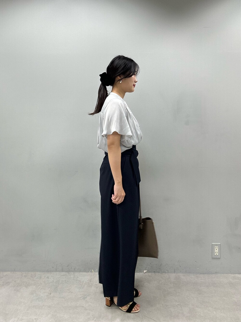 ブラウン系のショルダーバッグ、ブルー系のその他パンツ、グレー系のシャツ/ブラウスを着用したレディースの春コーディネートの2枚目の写真