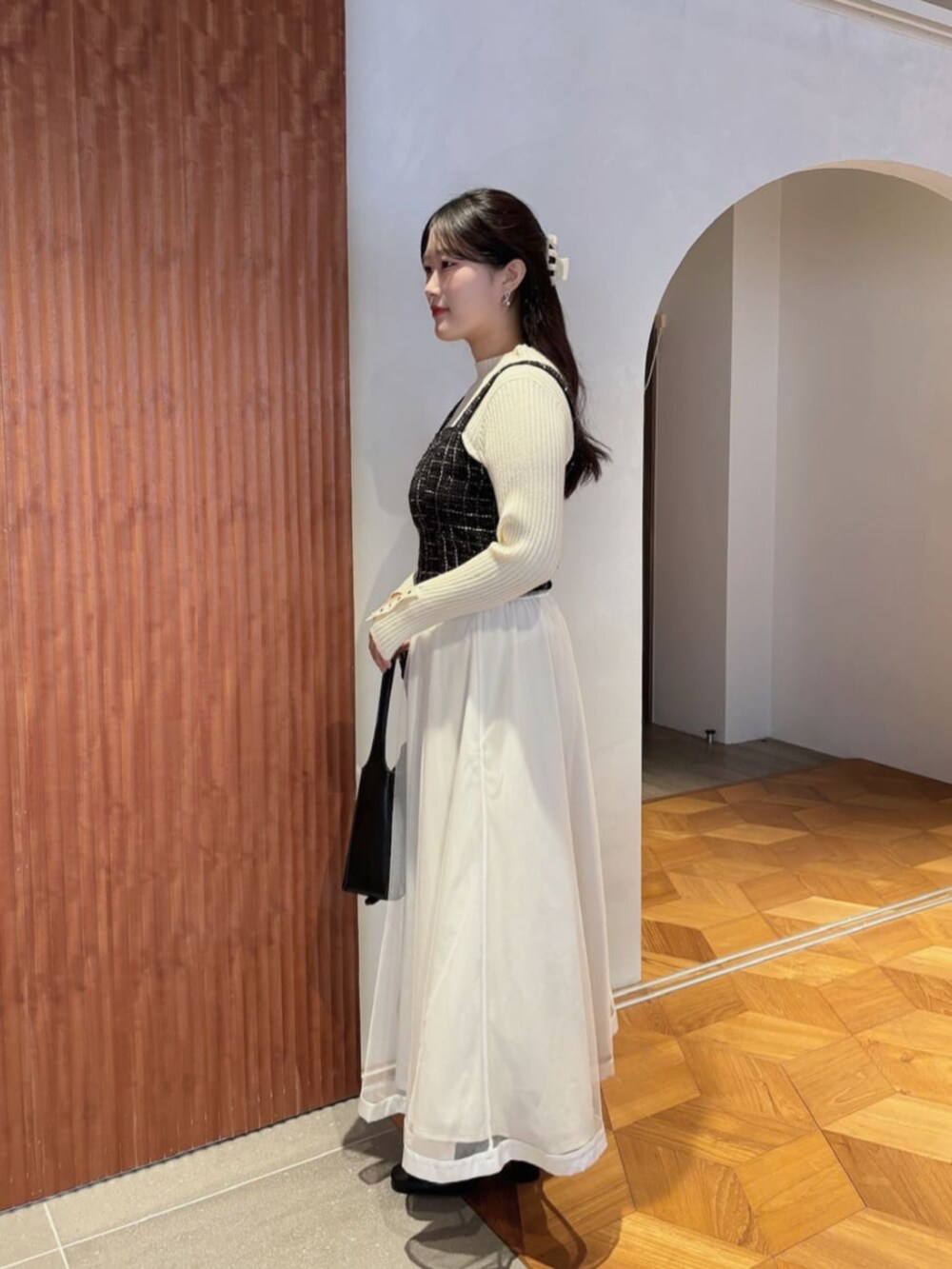 ホワイト系のスカート、ブラック系のシャツ/ブラウス、ホワイト系のニット/セーターを着用したレディースの秋コーディネートの2枚目の写真