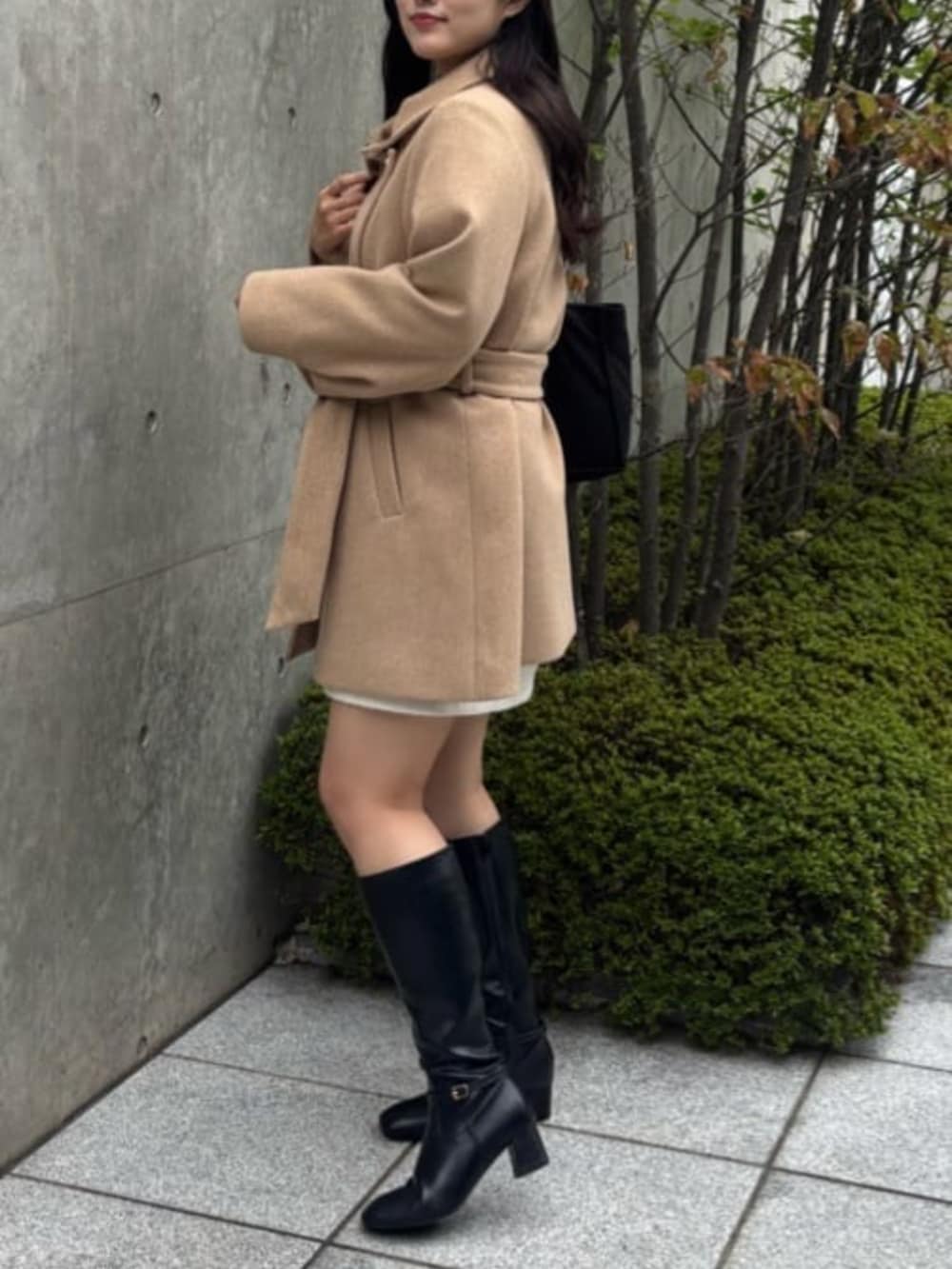 ブラック系のブーツ、ベージュ系のその他アウター、ホワイト系のスカートを着用したレディースの秋コーディネートの2枚目の写真